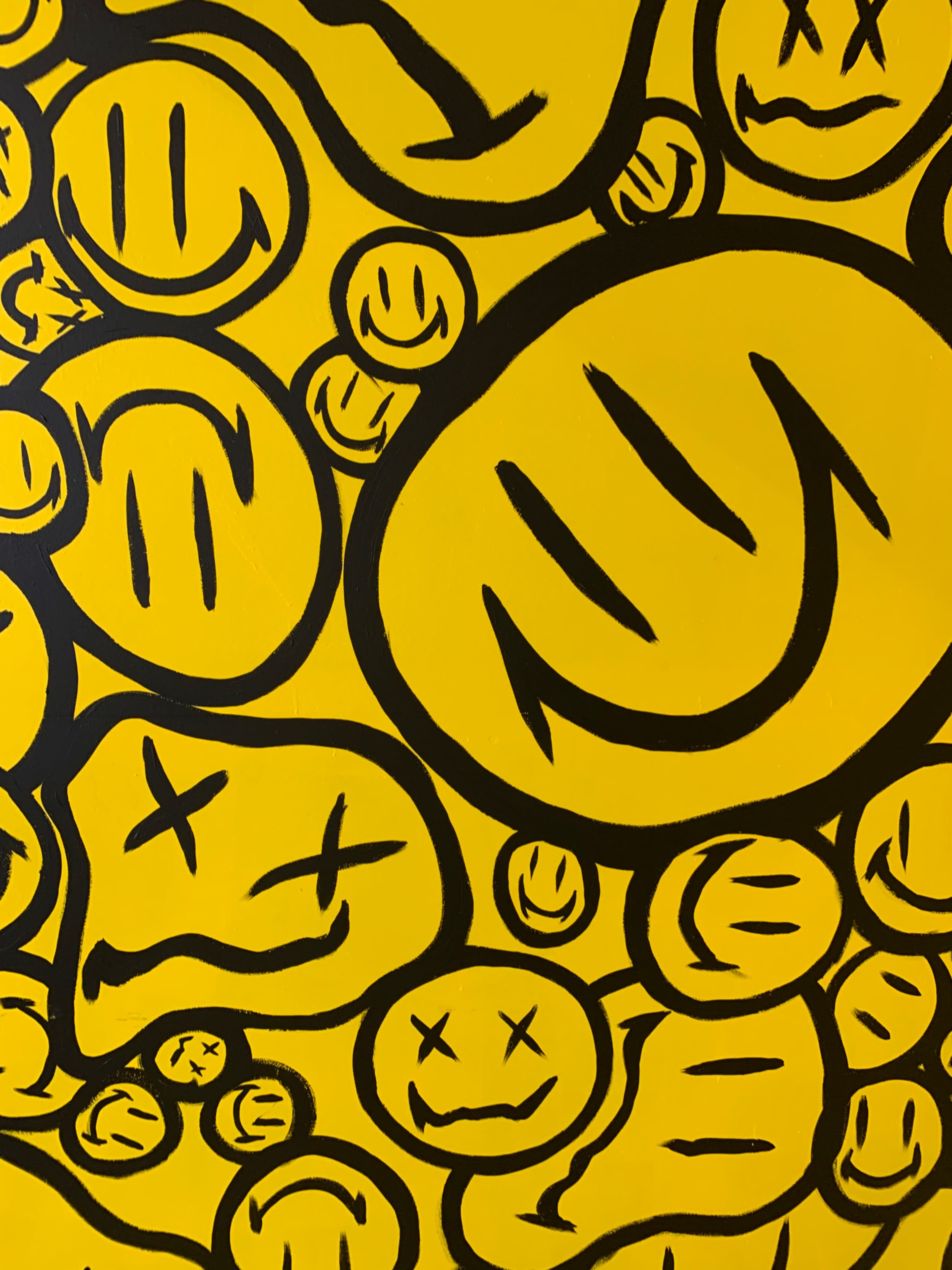 A pattern of various black smiley faces on a bright yellow background.