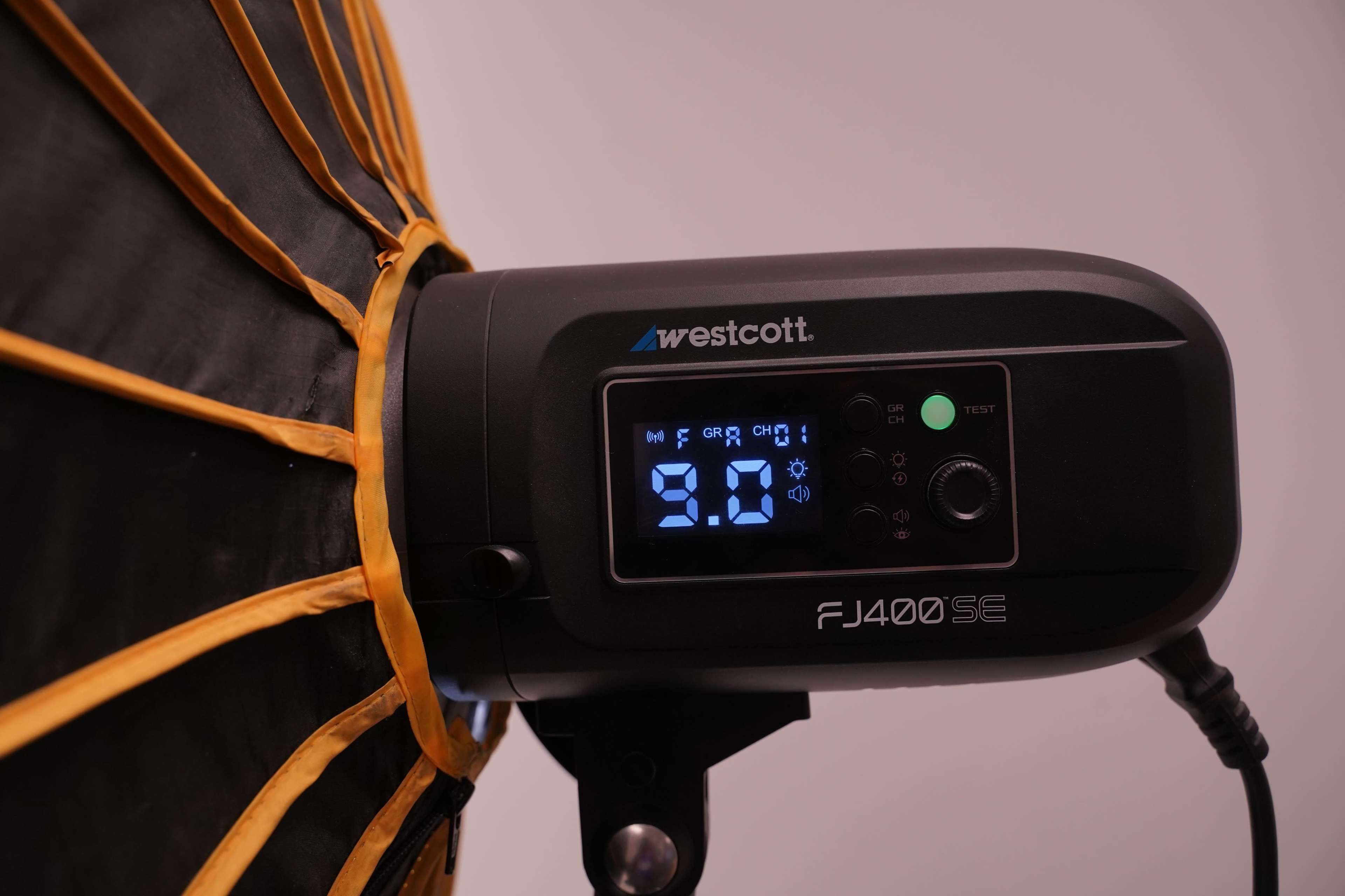 The image shows a Westcott FJ400SE studio strobe light with a digital display indicating a power setting of 9.0.