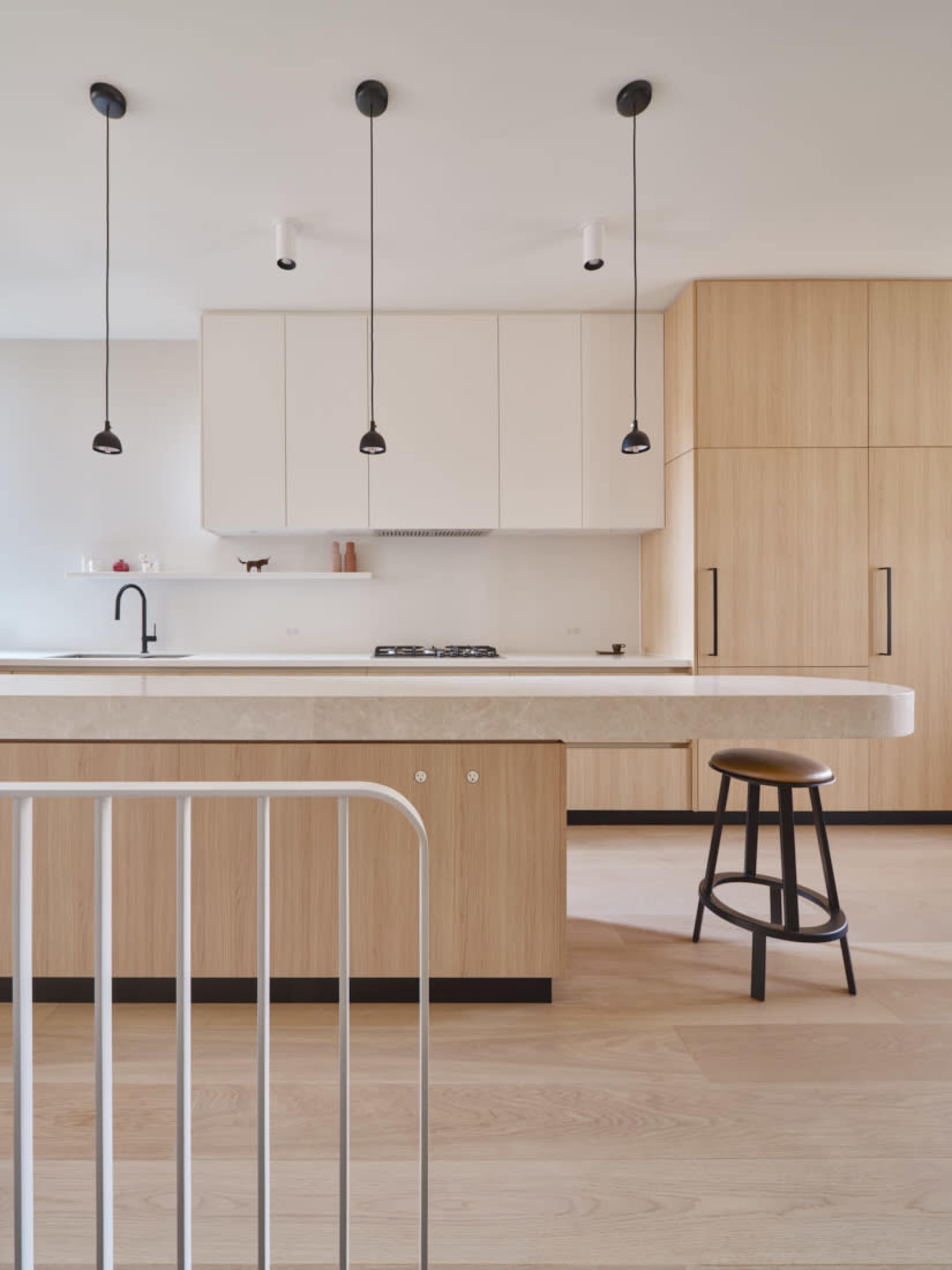 A modern kitchen featuring wooden cabinetry, a central island with a stone countertop, and pendant lights hanging from the ceiling.