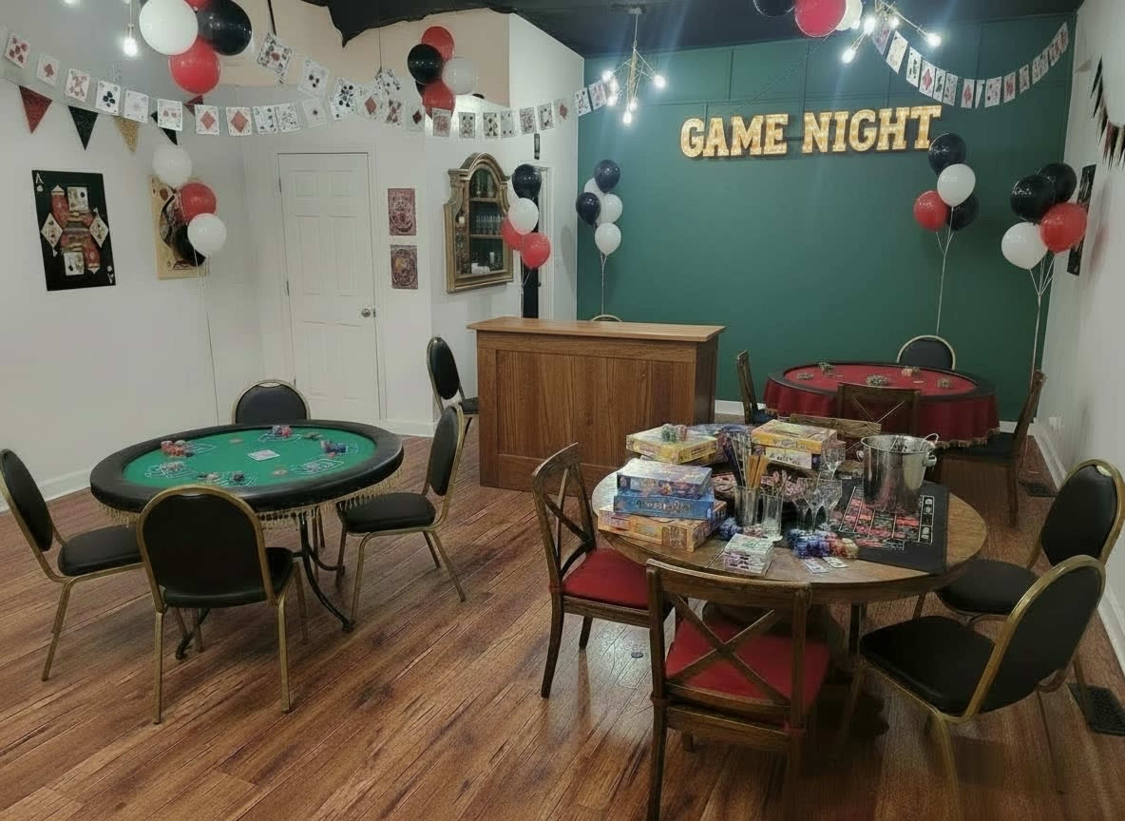 The image shows a game night setup in a room with two tables, one for poker and another for board games, along with decorations of balloons and a "GAME NIGHT" sign on the wall.