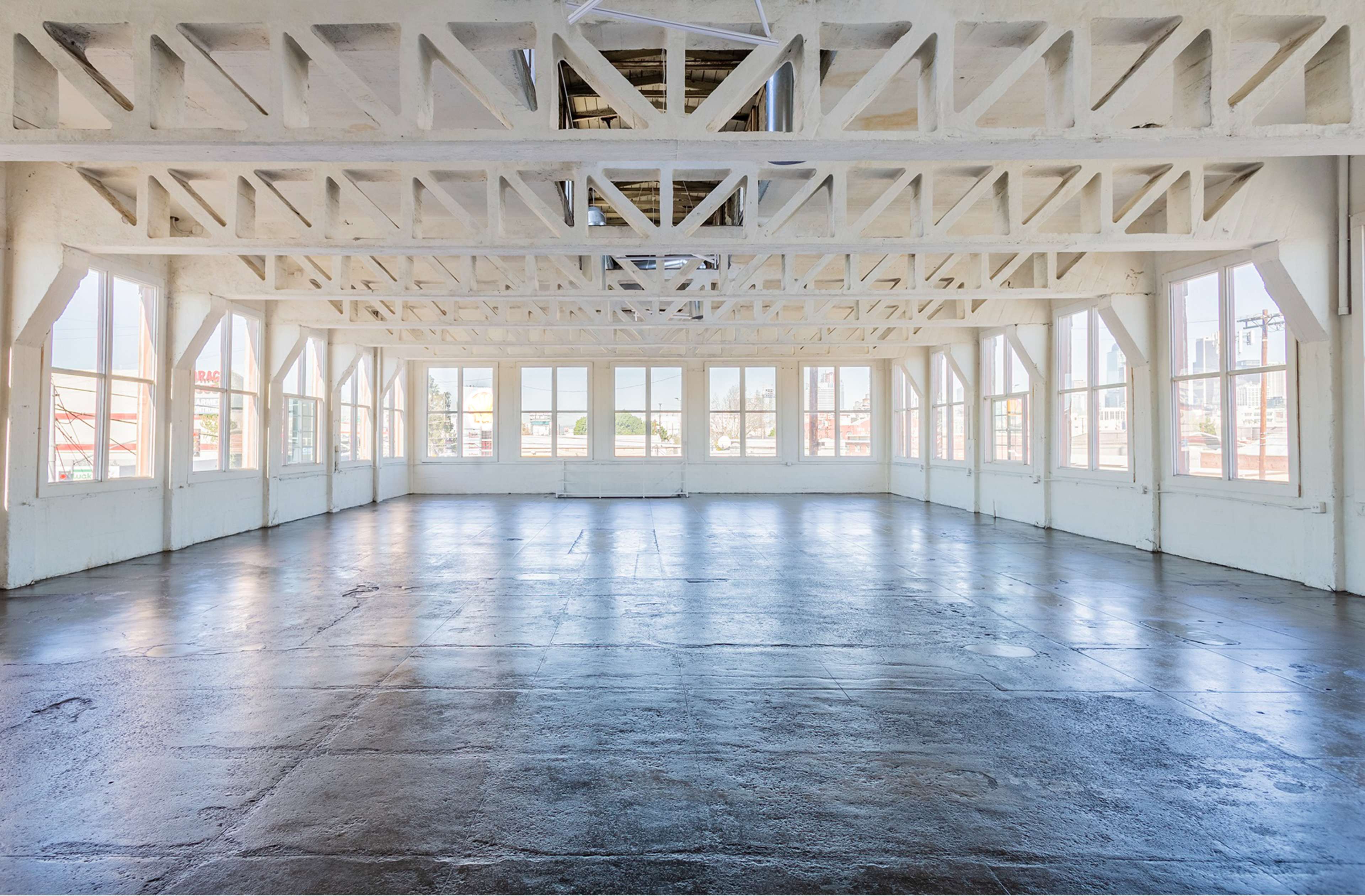 A spacious, well-lit room with large windows and exposed wooden beams.