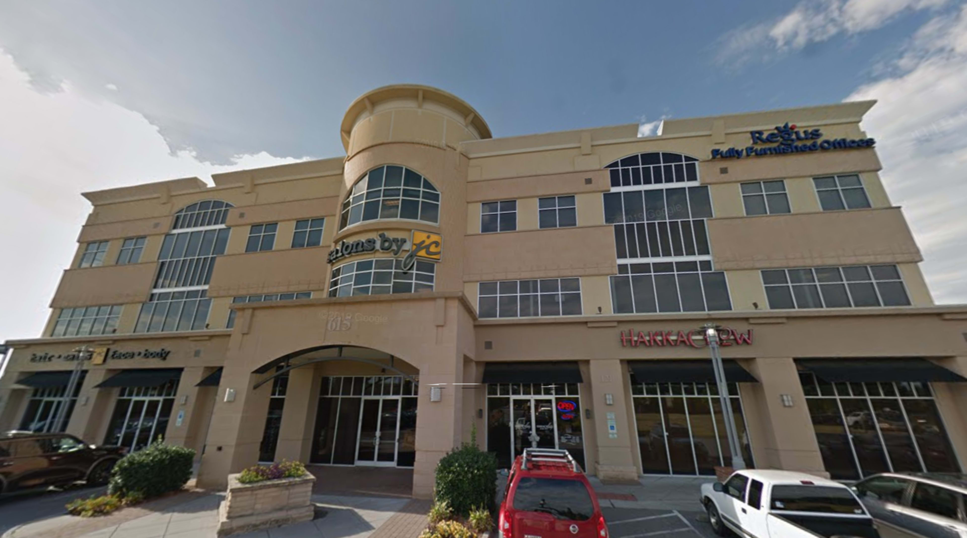 The image shows a multi-story commercial building featuring a mix of retail spaces and offices, with signage for "Regus" and "Hakka Stew" visible.