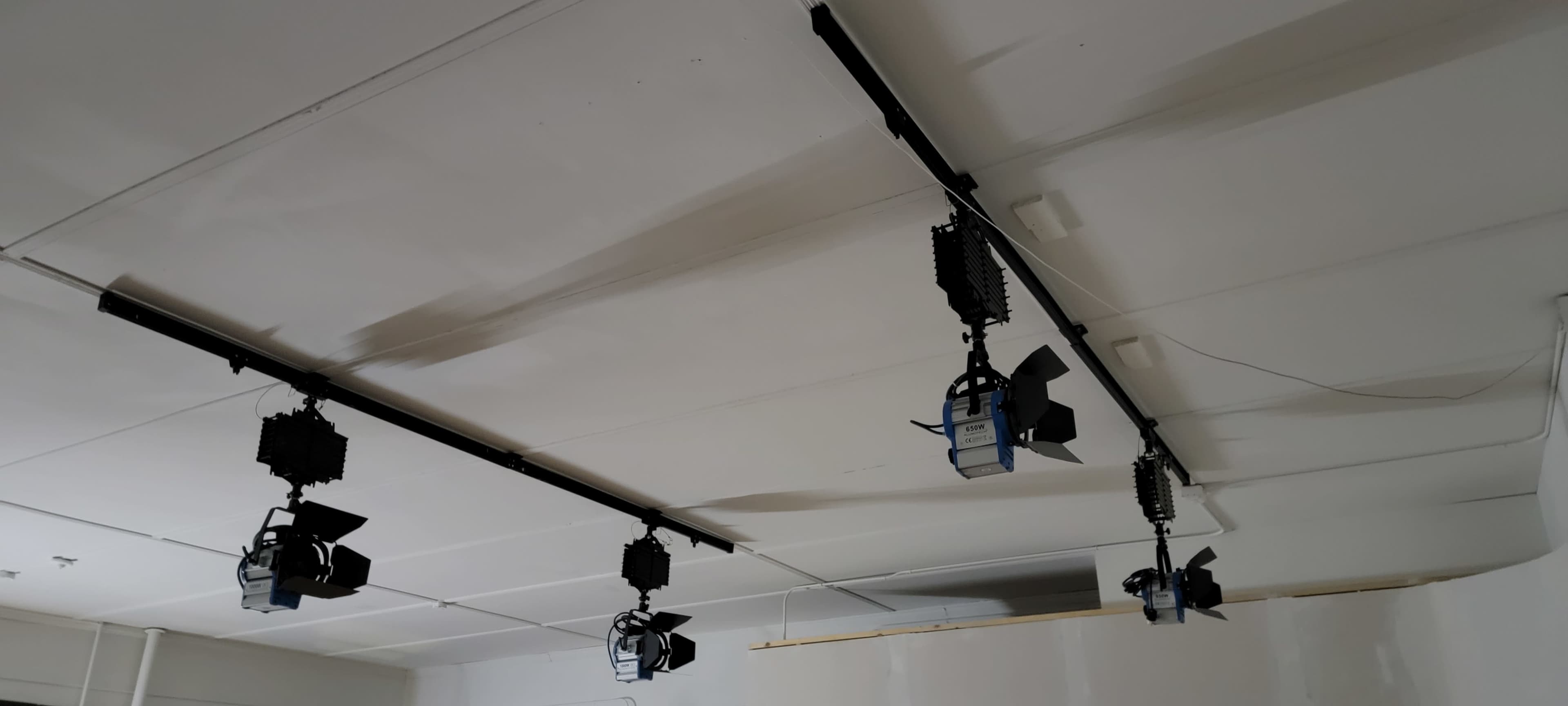 A ceiling with several stage lights mounted on a black track.
