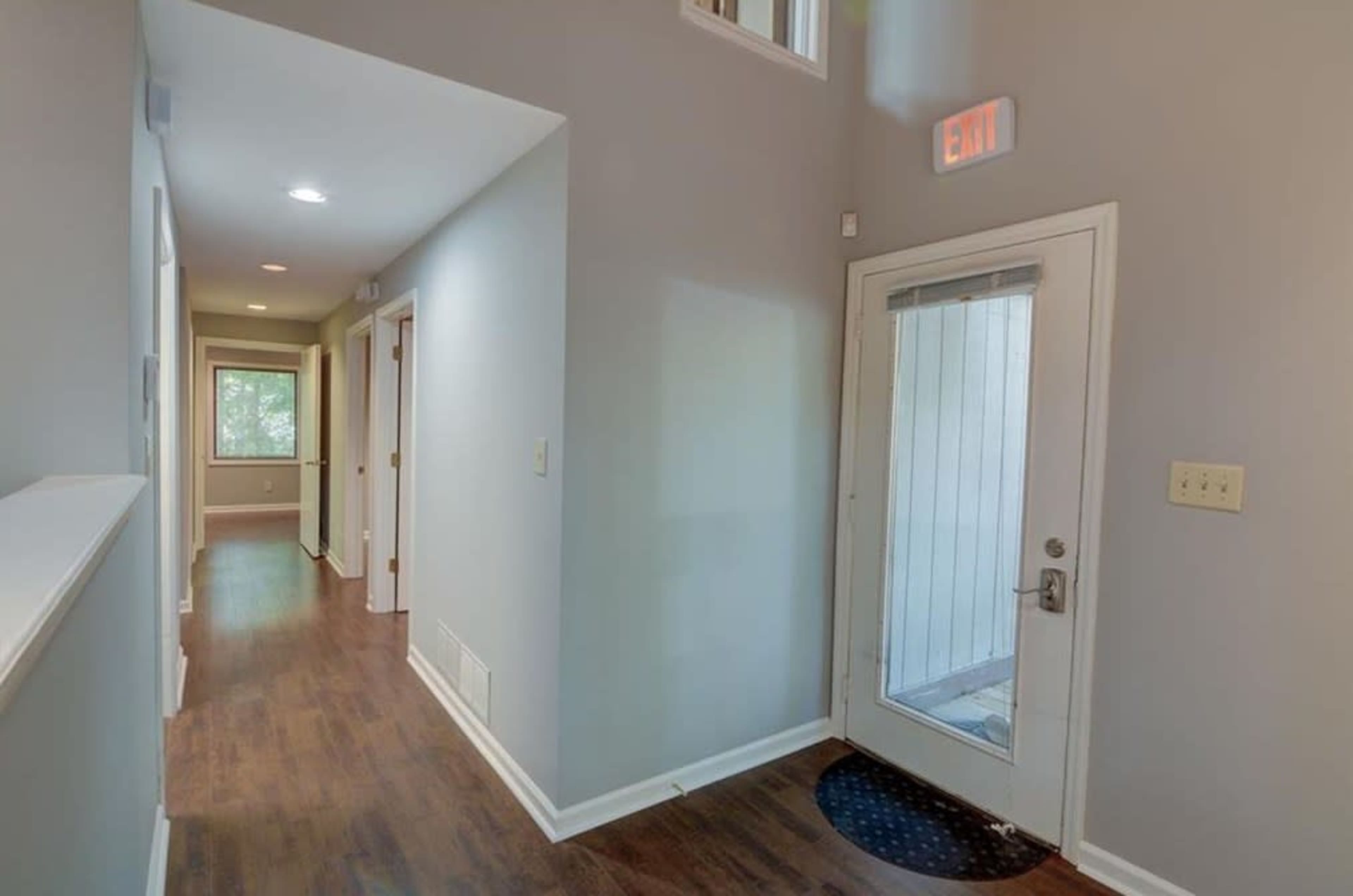 The image shows a hallway with a front door on the right and several doorways on the left, leading to other rooms.