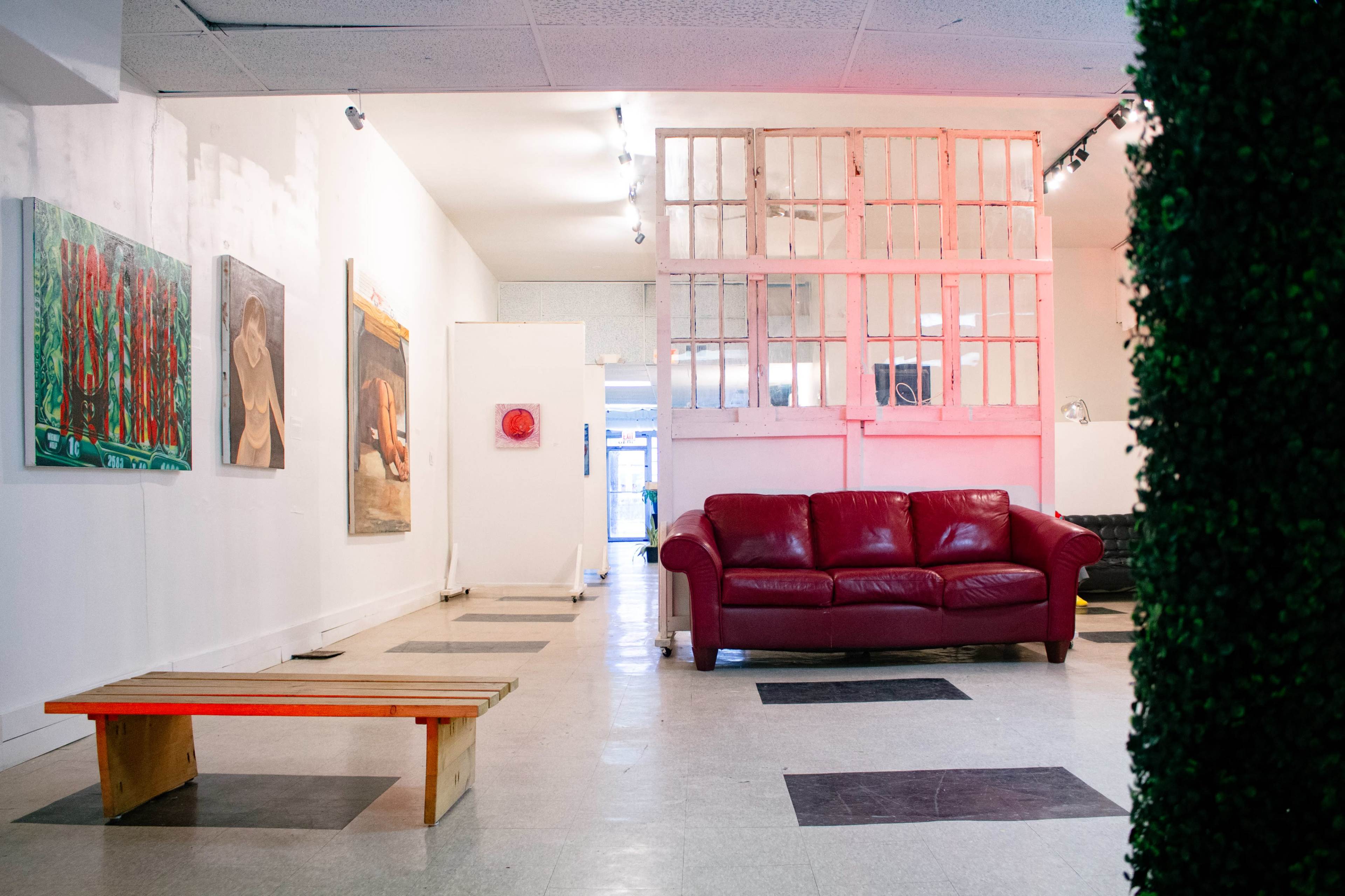 The image shows an art gallery with a red couch and artwork hanging on the walls, illuminated by bright lighting.