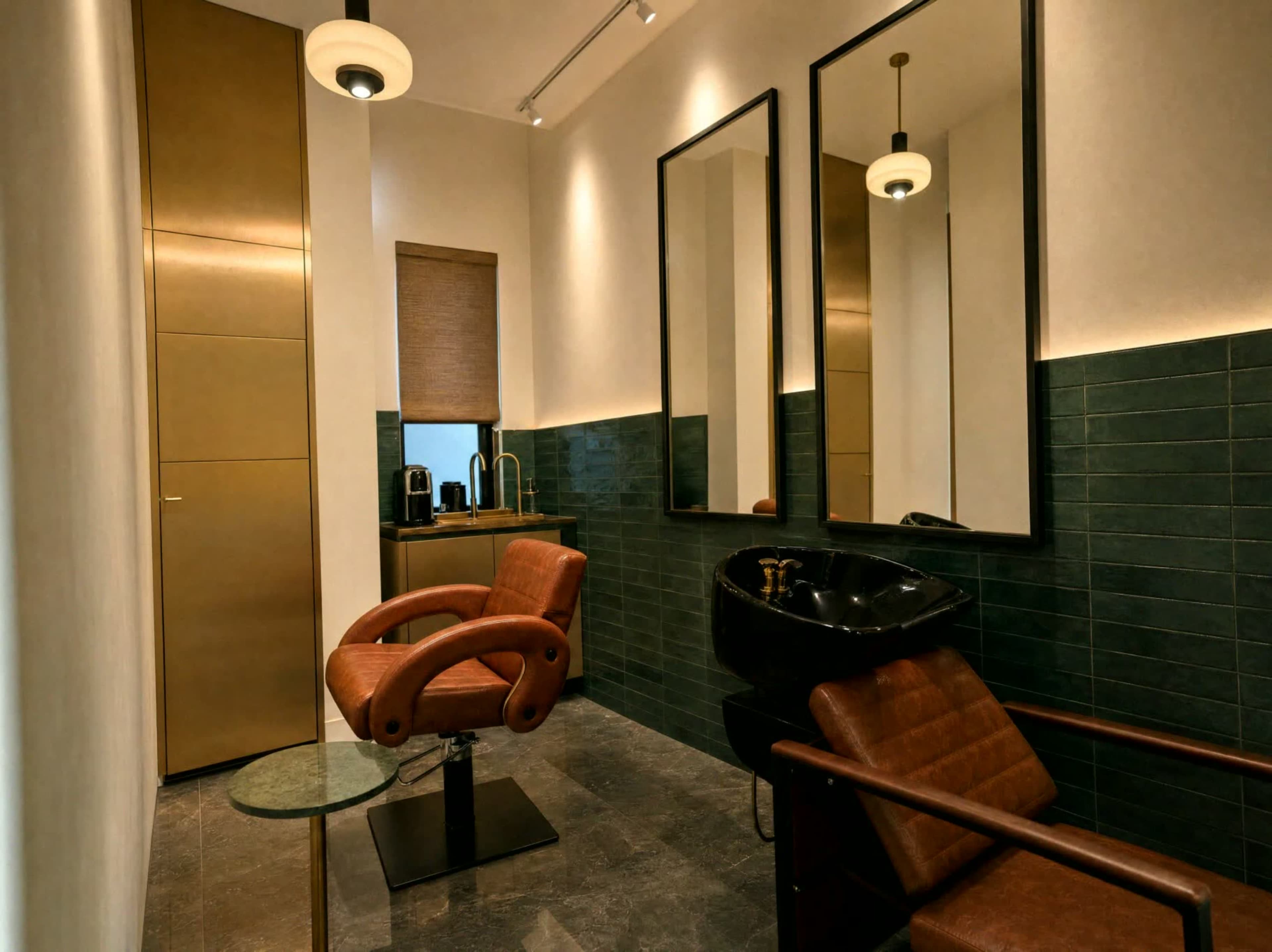 The image shows a modern salon interior featuring two salon chairs, a shampoo basin, large mirrors, and stylish cabinetry adorned in gold and green tiles.