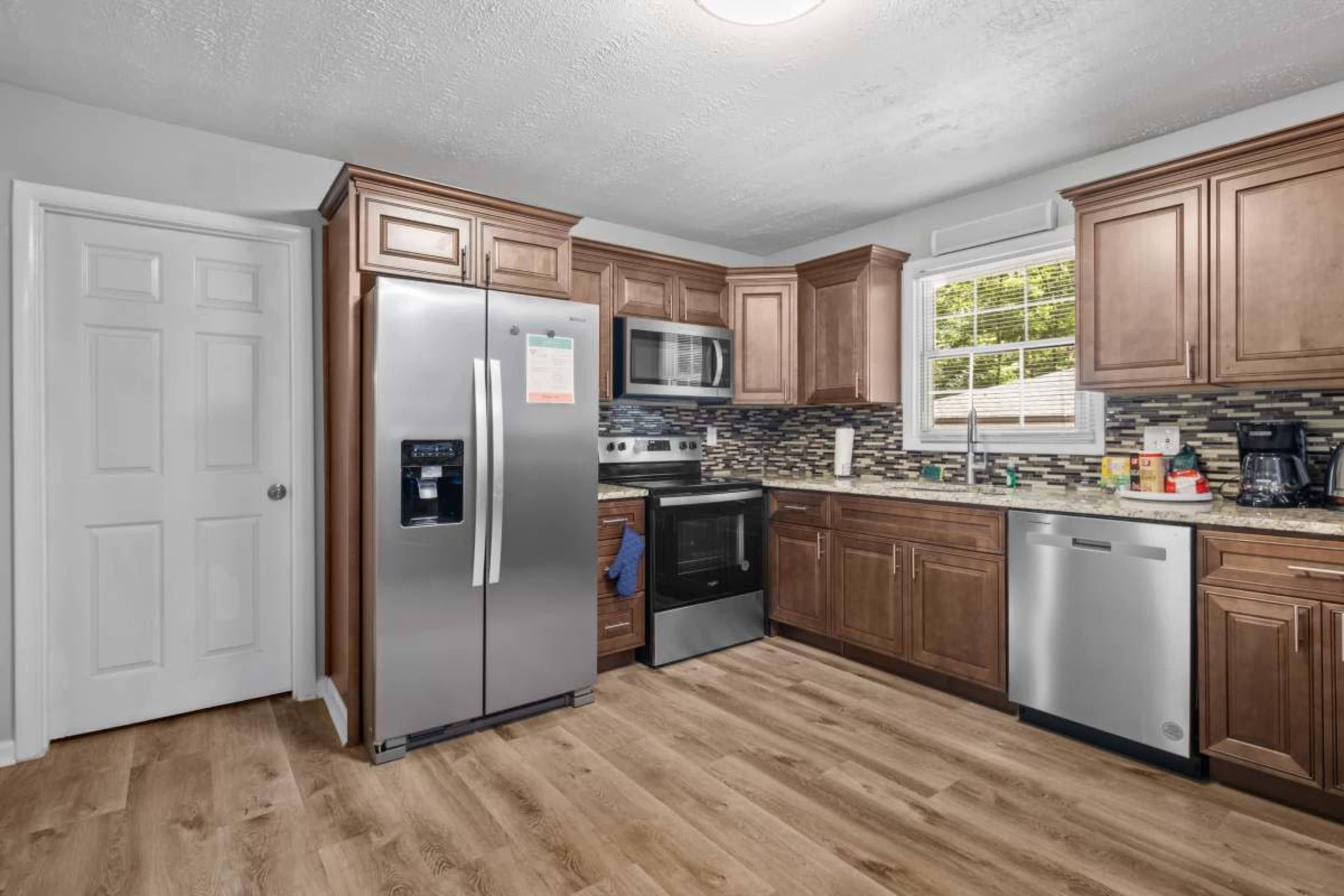 The image shows a modern kitchen featuring wooden cabinets, stainless steel appliances, and a tiled backsplash.