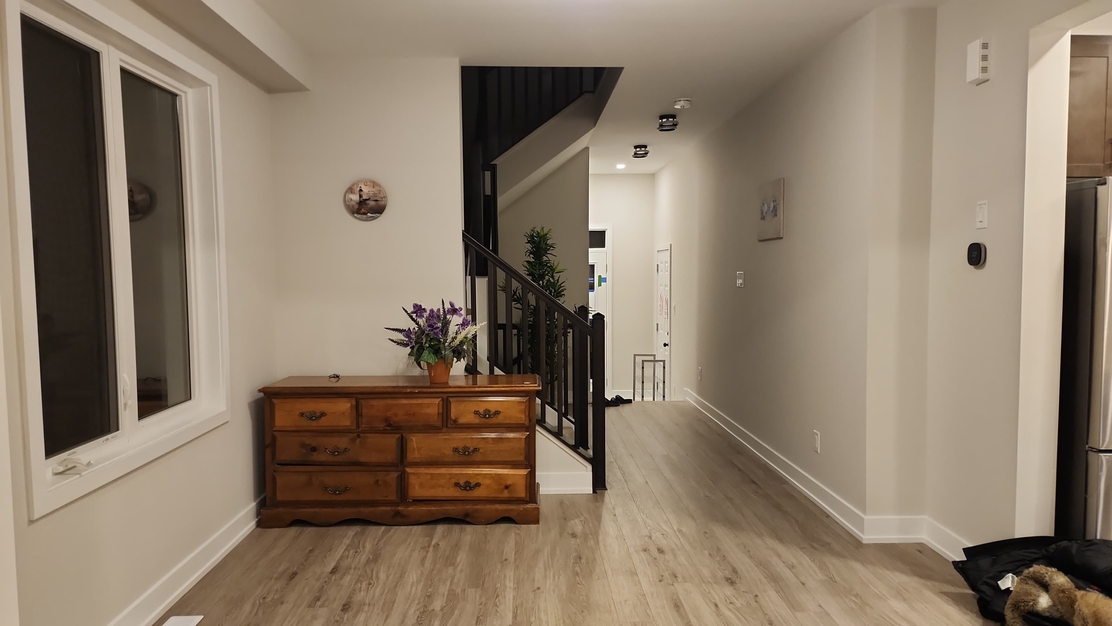 The image shows a hallway with a wooden dresser and a staircase leading to an upper level.
