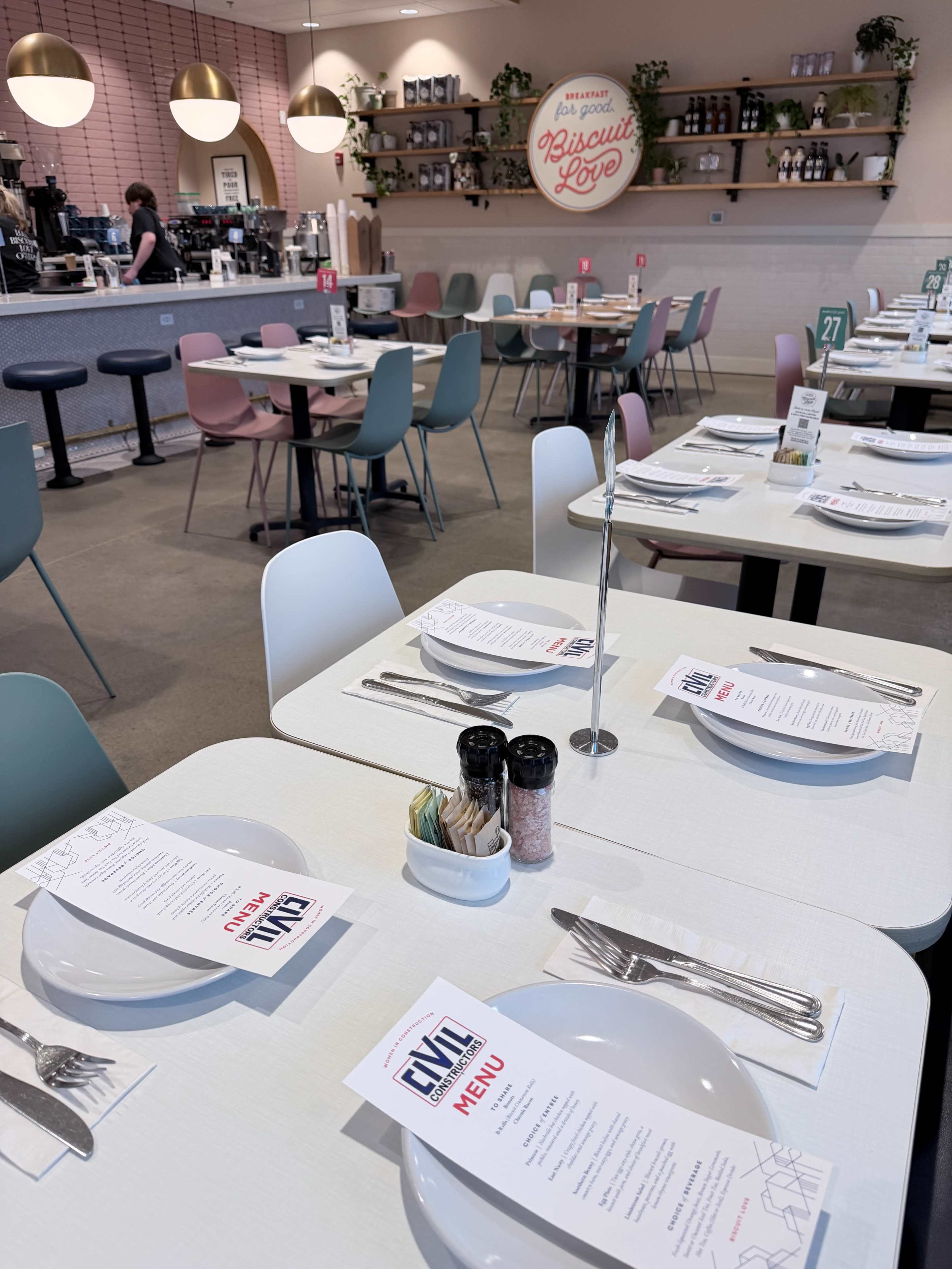 A brightly lit café features neatly arranged tables with menus and condiments, showcasing a modern interior design.