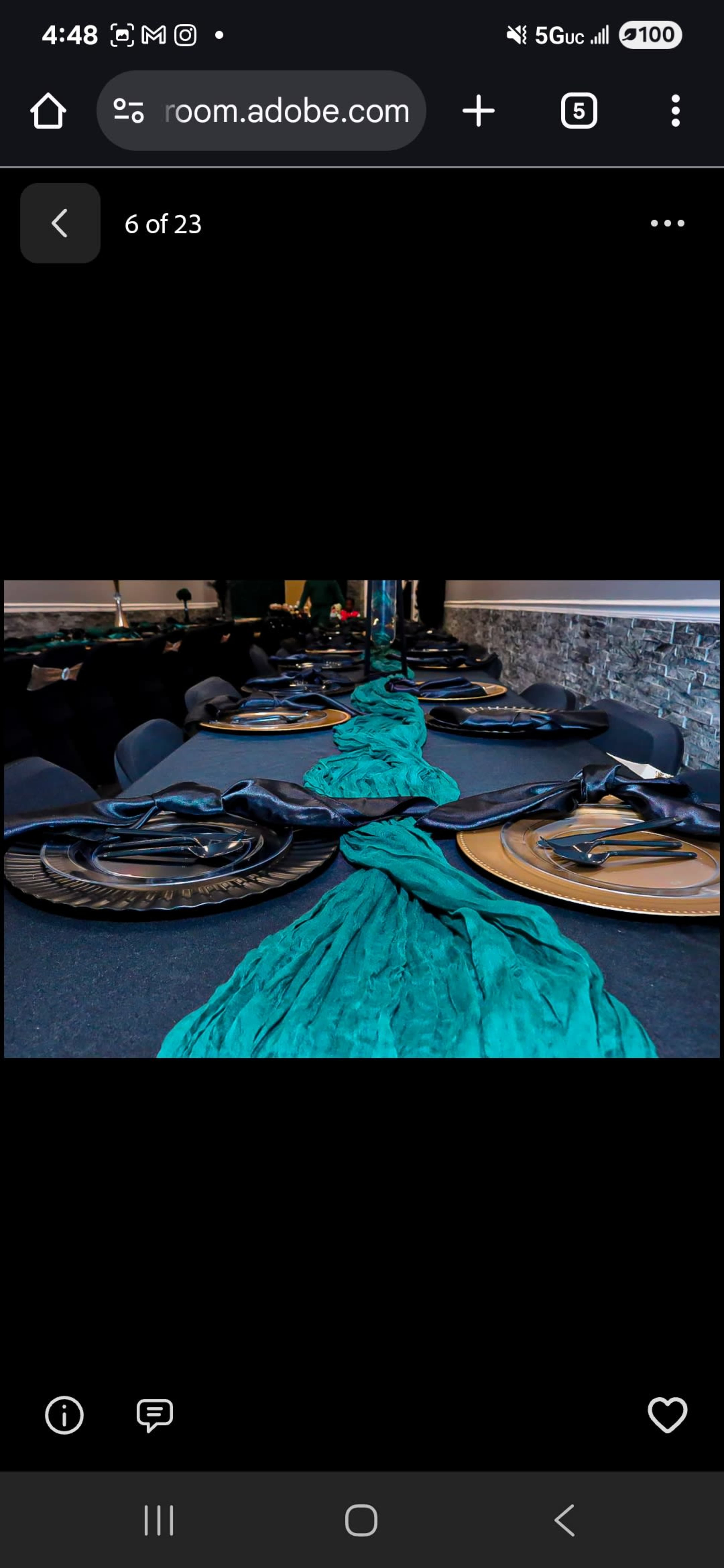A long teal fabric drapes across a table set with dark plates and cutlery in a modern dining space.