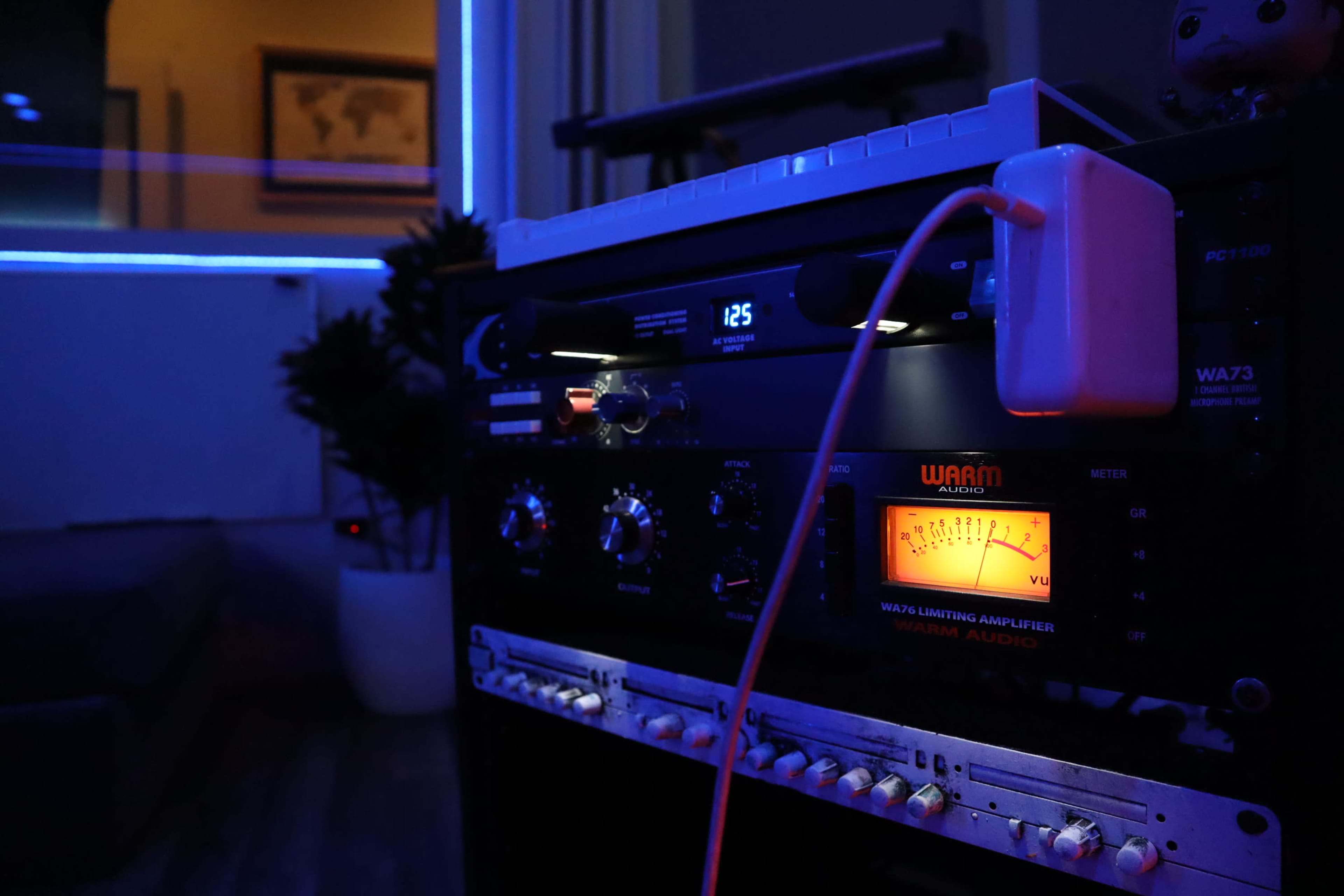 A close-up view of audio equipment with various knobs and lights, set against a dimly lit room with blue ambient lighting.