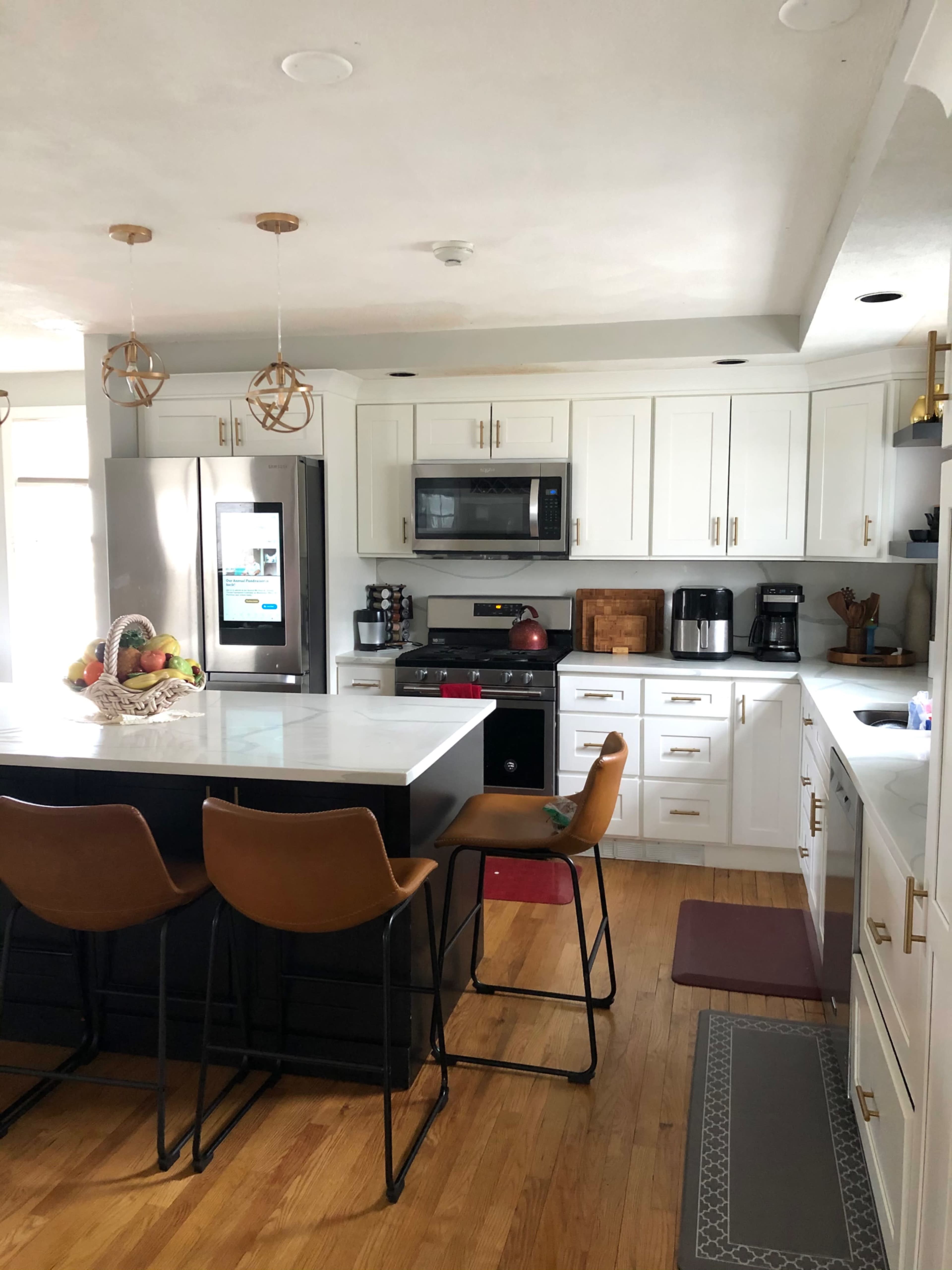 A modern kitchen featuring a large island with seating, white cabinetry, and stainless steel appliances.