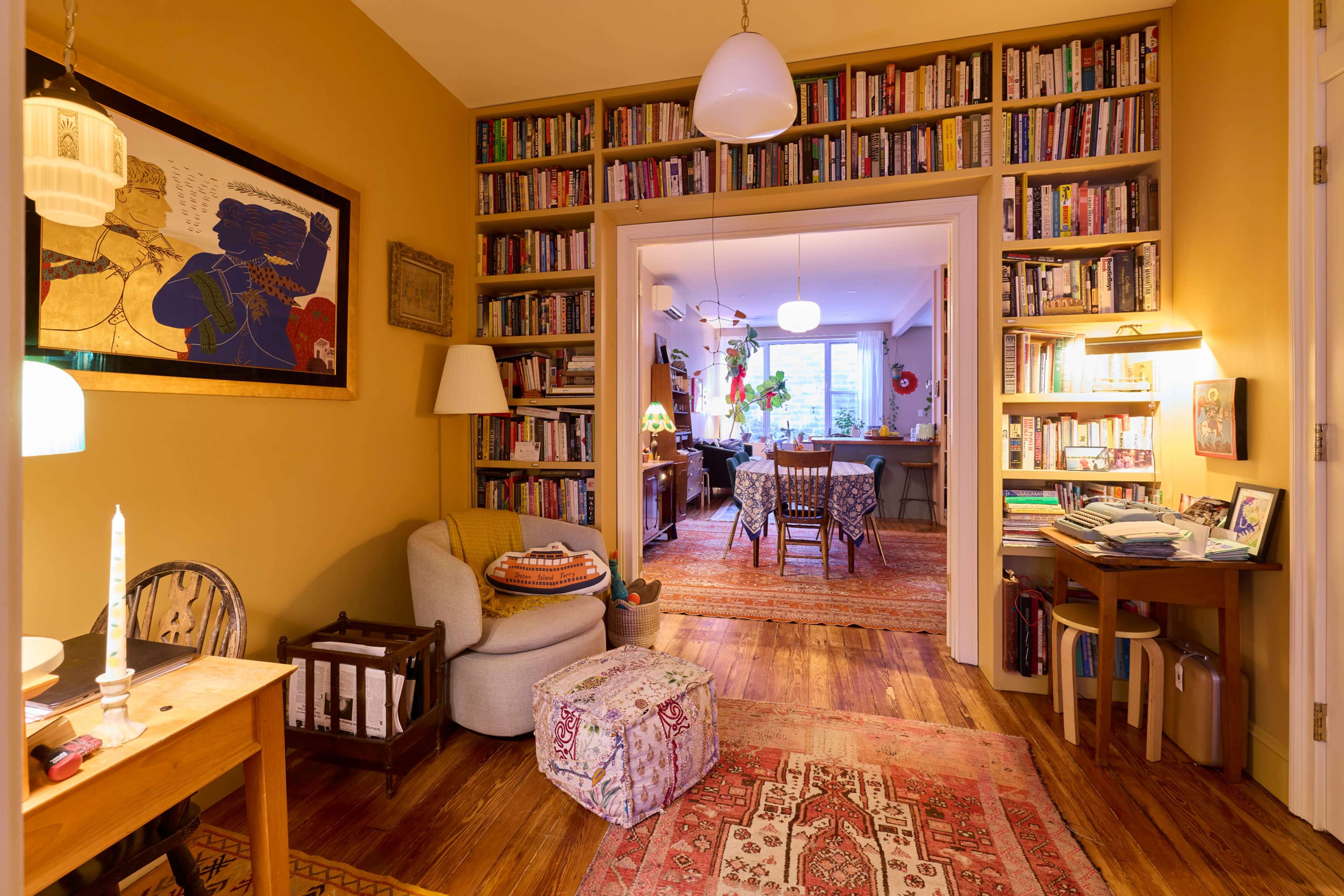 A cozy interior features a hallway lined with bookshelves, leading to a living space filled with furniture and decor.