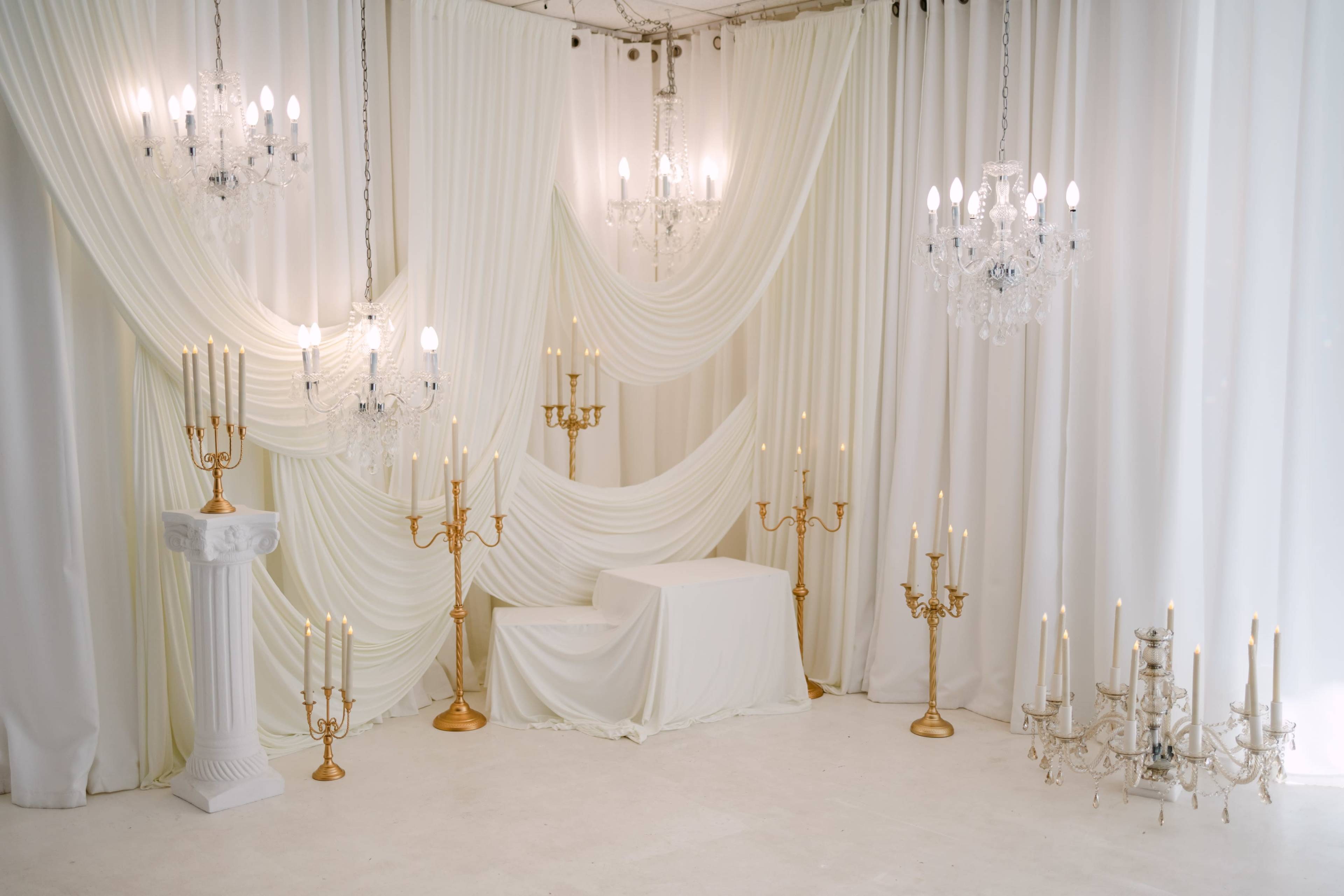 The scene features a elegantly draped room with white fabric and multiple chandeliers and candelabras.
