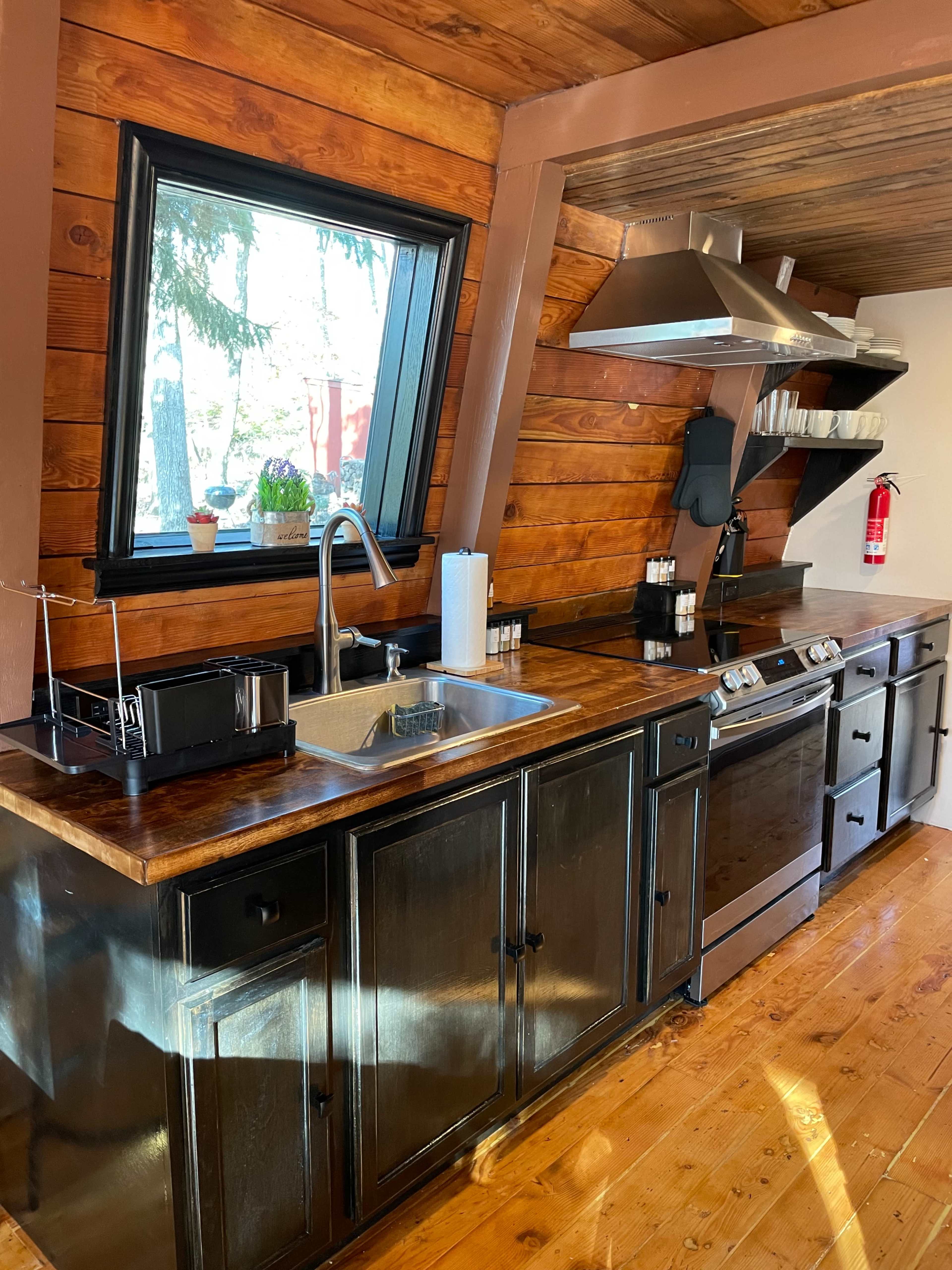 A modern kitchen with wooden walls, a sleek countertop, a sink, a stove, and various kitchen appliances arranged neatly.