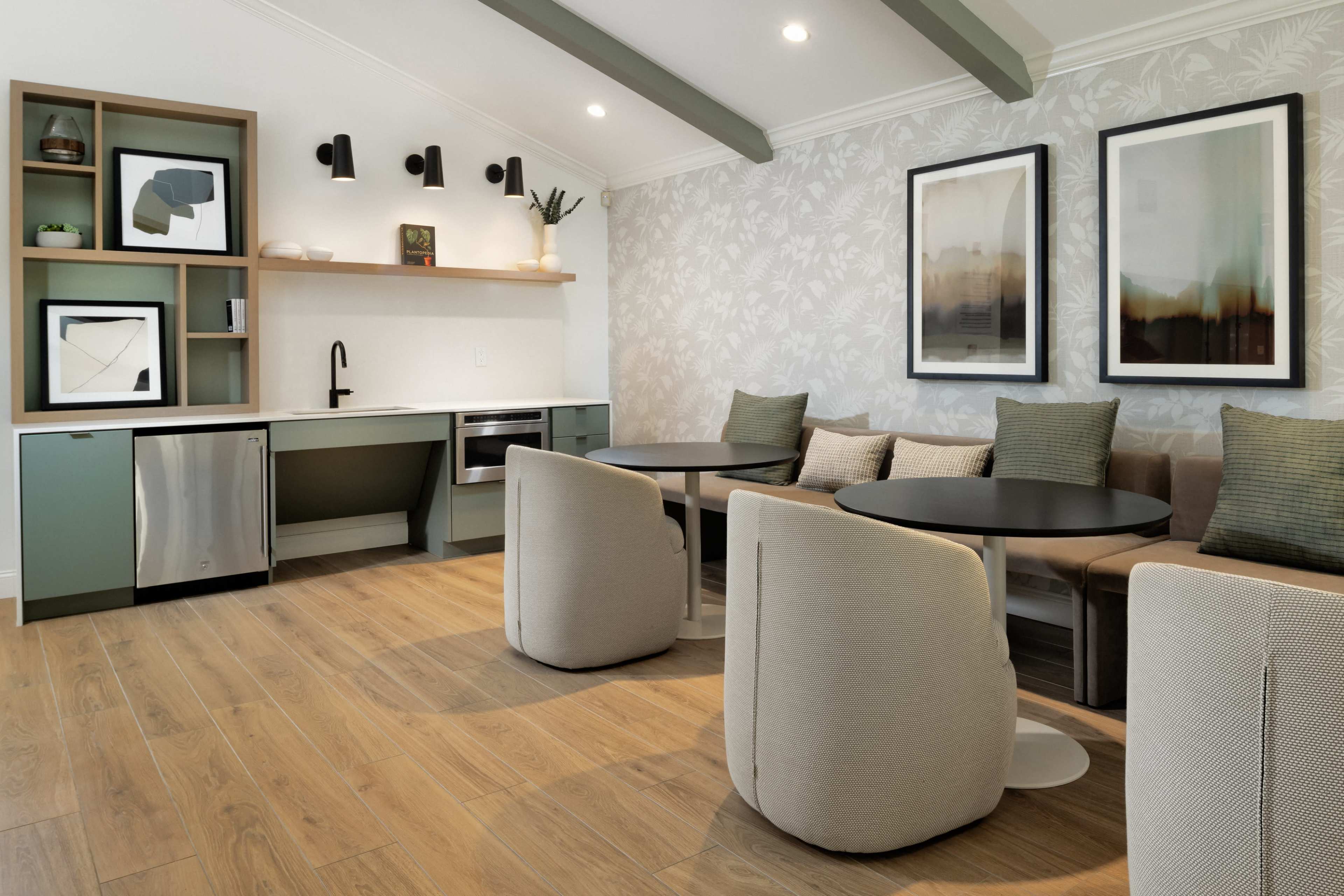 The image shows a modern kitchen and dining area with a green and beige color scheme, featuring a built-in seating nook, round tables, and stylish wall decor.
