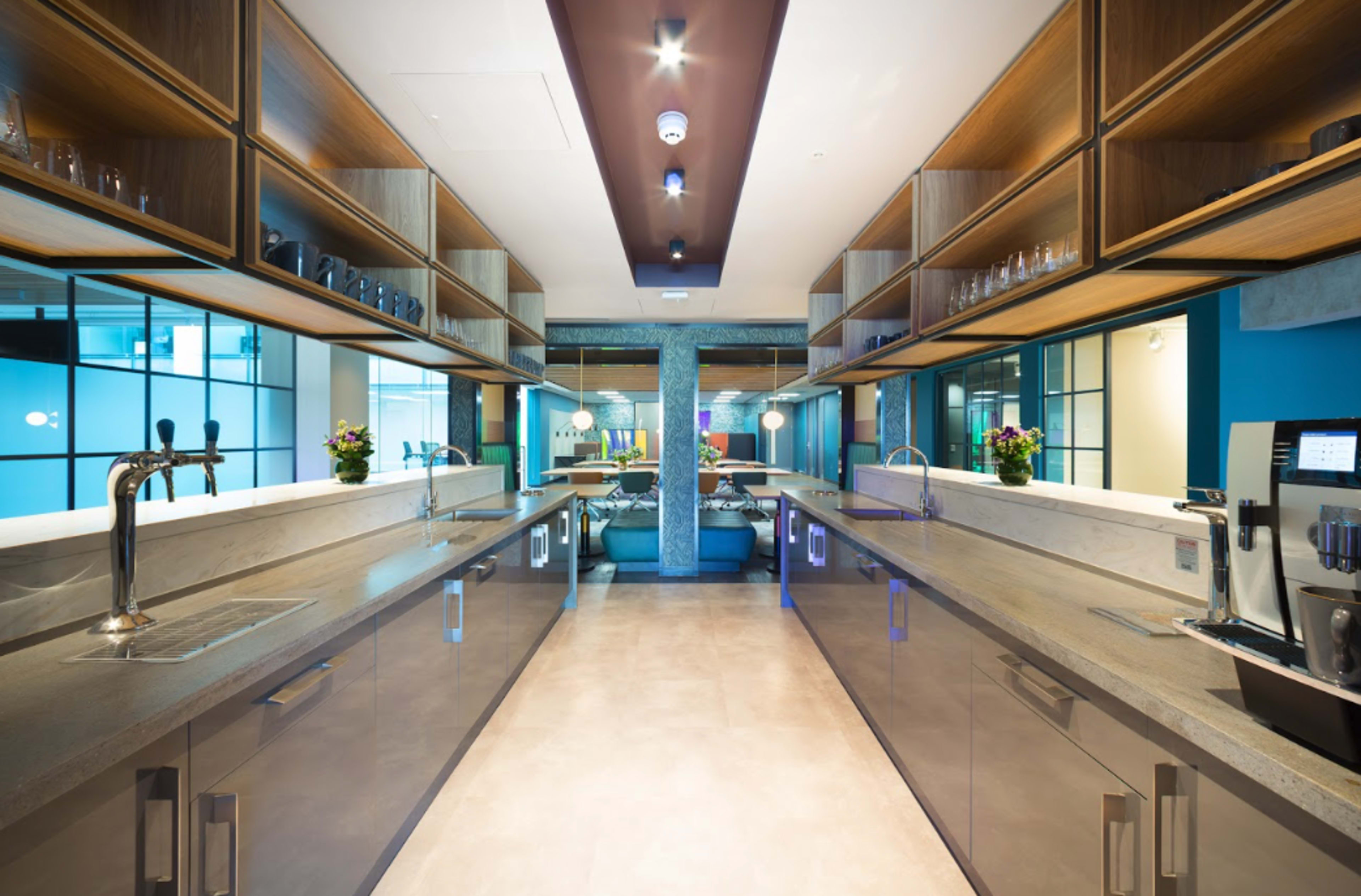 A modern kitchen features sleek countertops, open shelving, and stainless steel appliances along both sides.