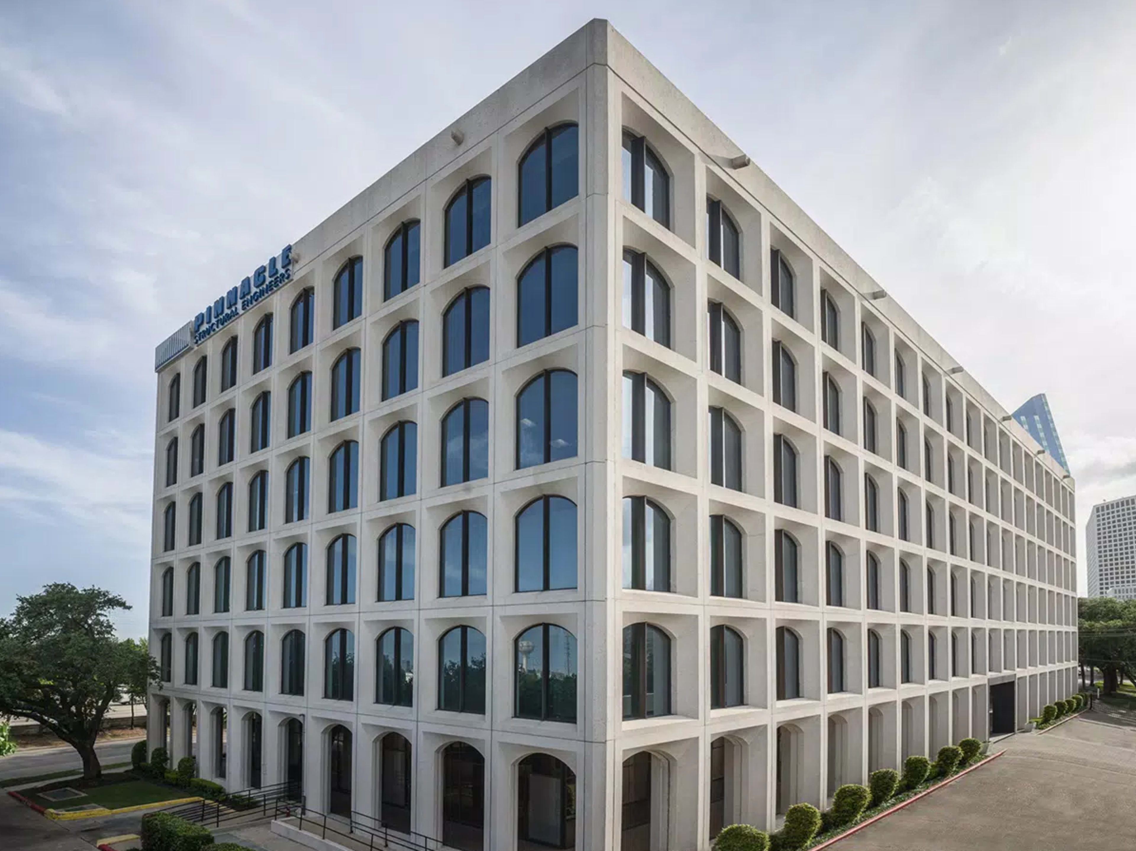 The image shows a modern commercial building with a distinctive geometric facade, featuring numerous large windows and a structured concrete design.