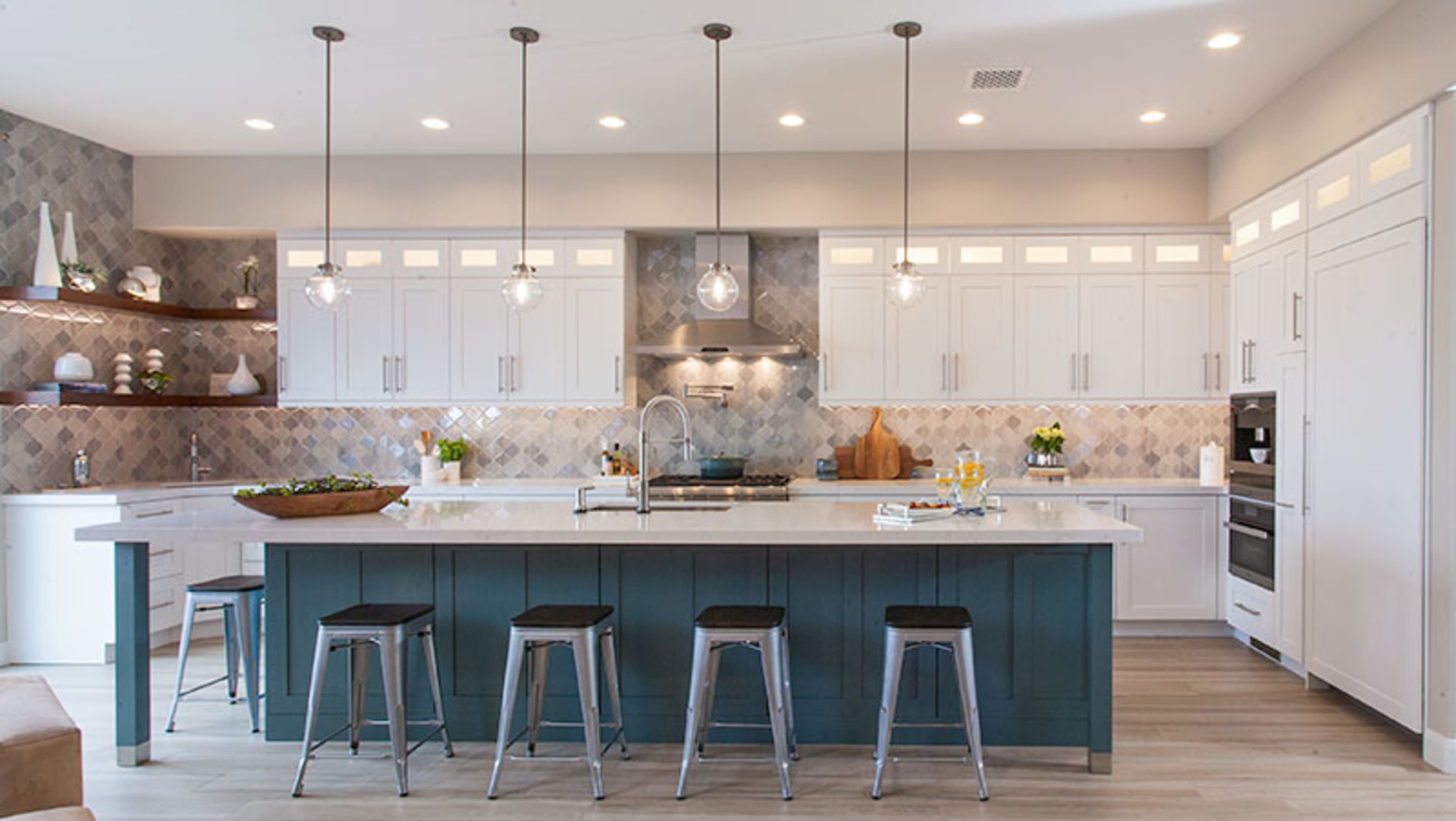 The image shows a modern kitchen with white cabinets, a gray tile backsplash, and a large island with bar stools.