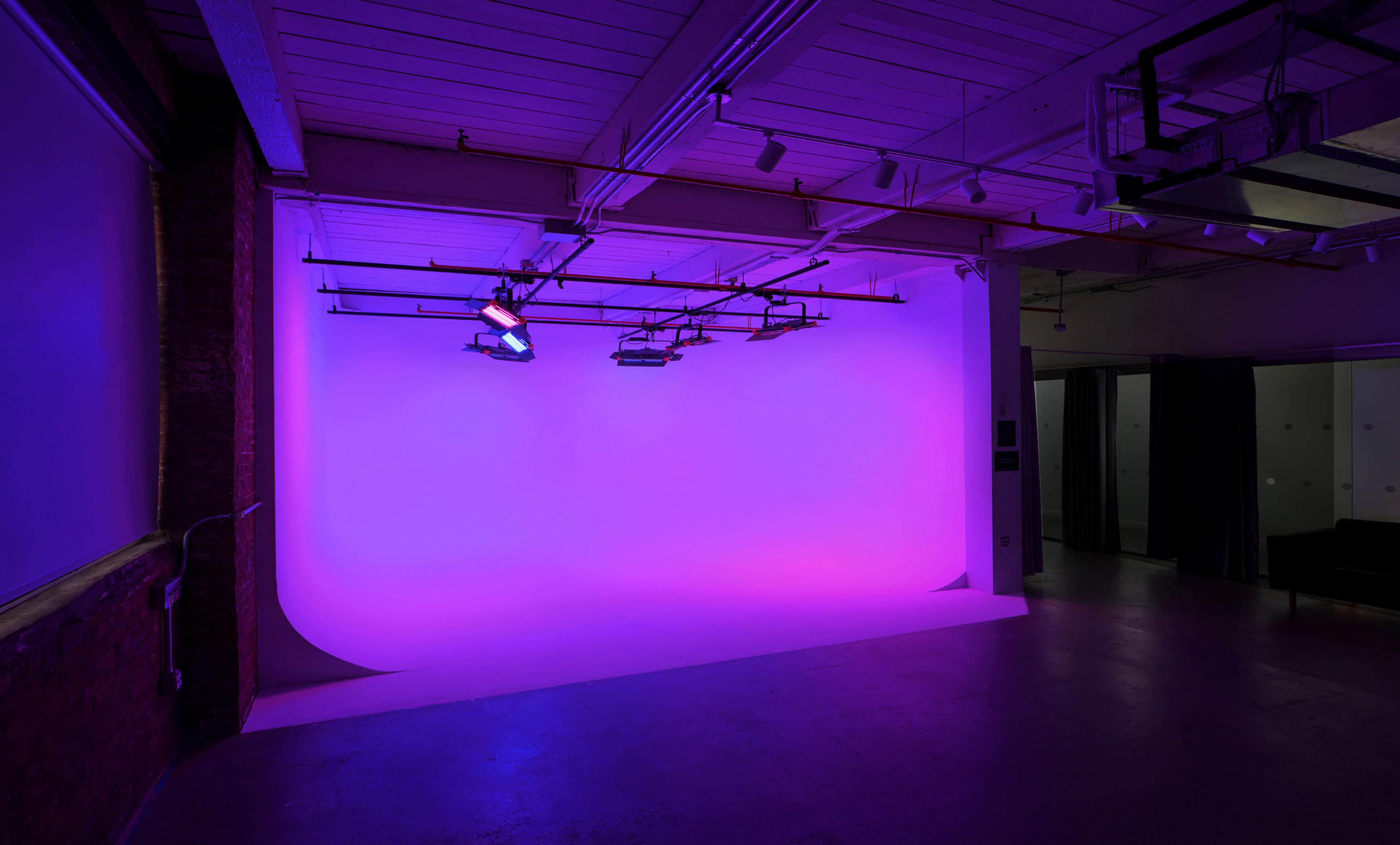 A photography studio with a purple backdrop and overhead lighting.