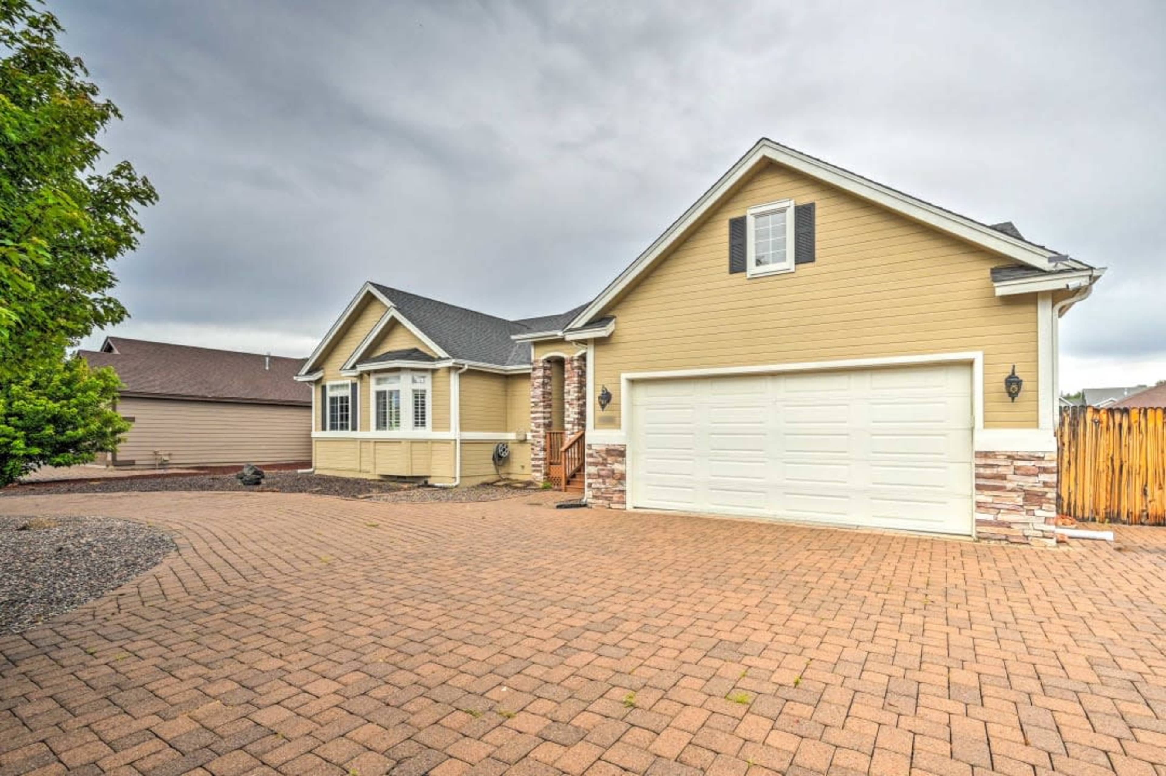 A single-story house with a beige exterior, a stone accent, and a paved driveway leading to a two-car garage.