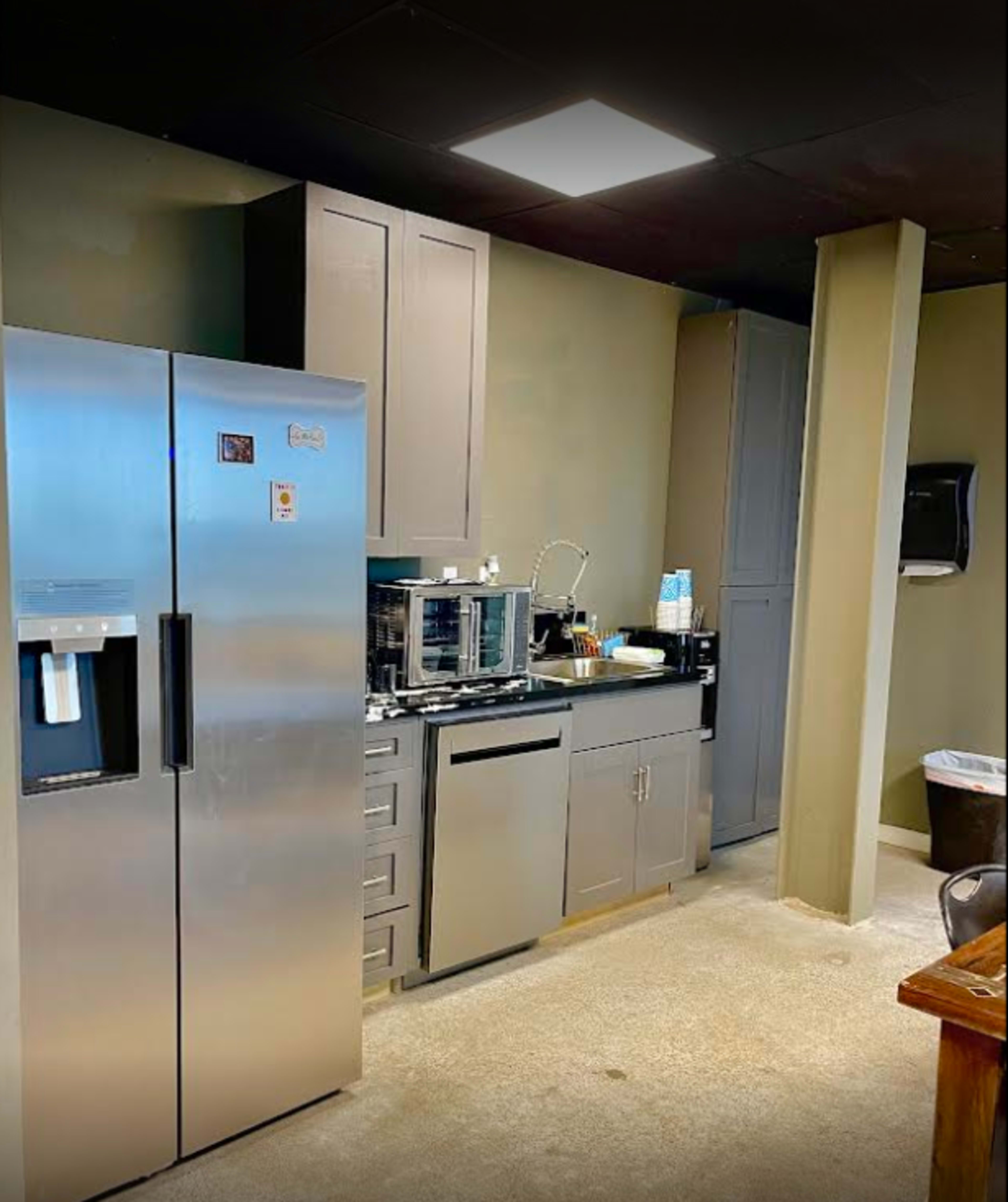A modern kitchen featuring stainless steel appliances, including a refrigerator and microwave, set against light green walls.
