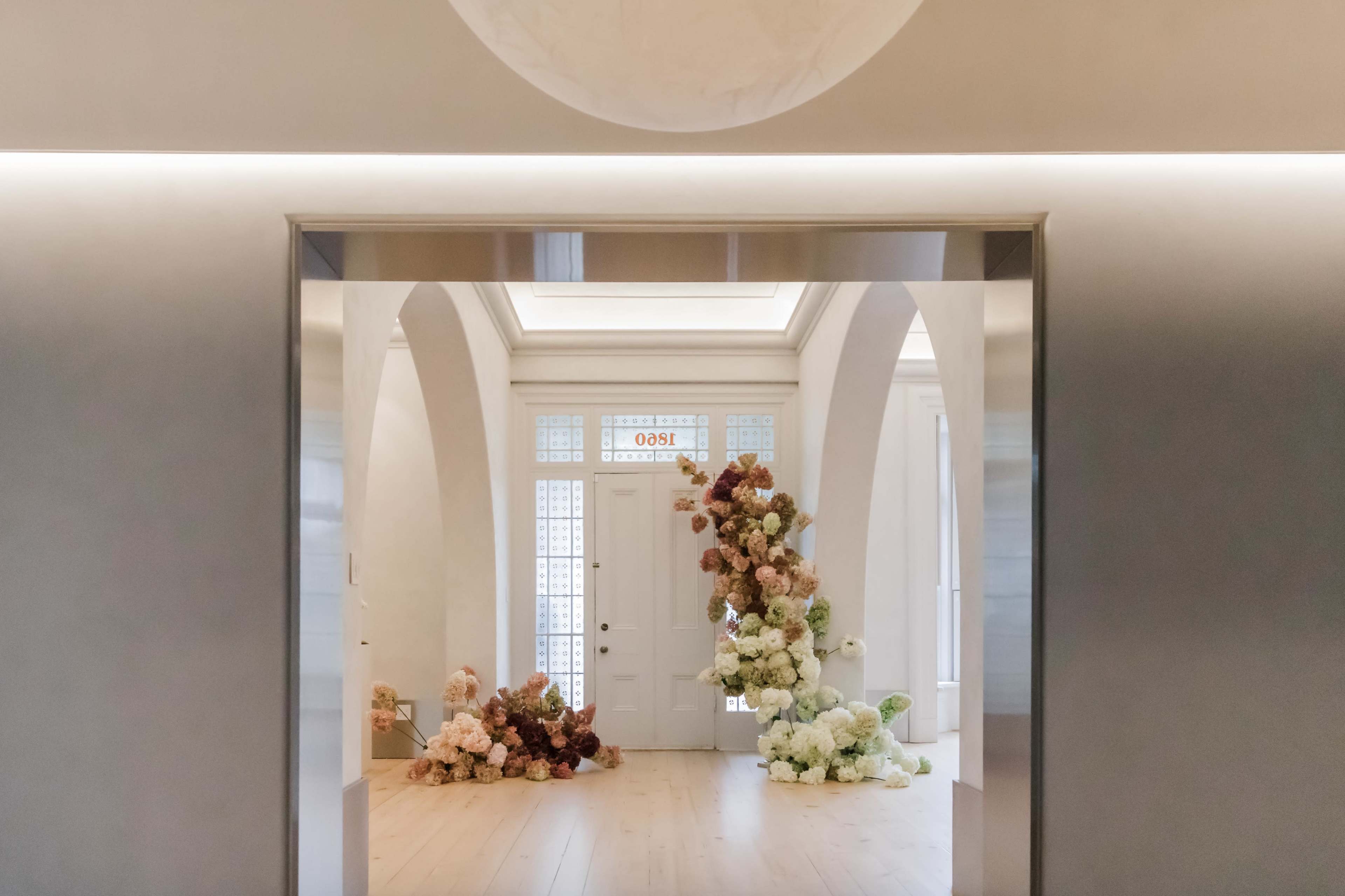 A spacious entryway features a doorway framed by large arrangements of multicolored flowers.