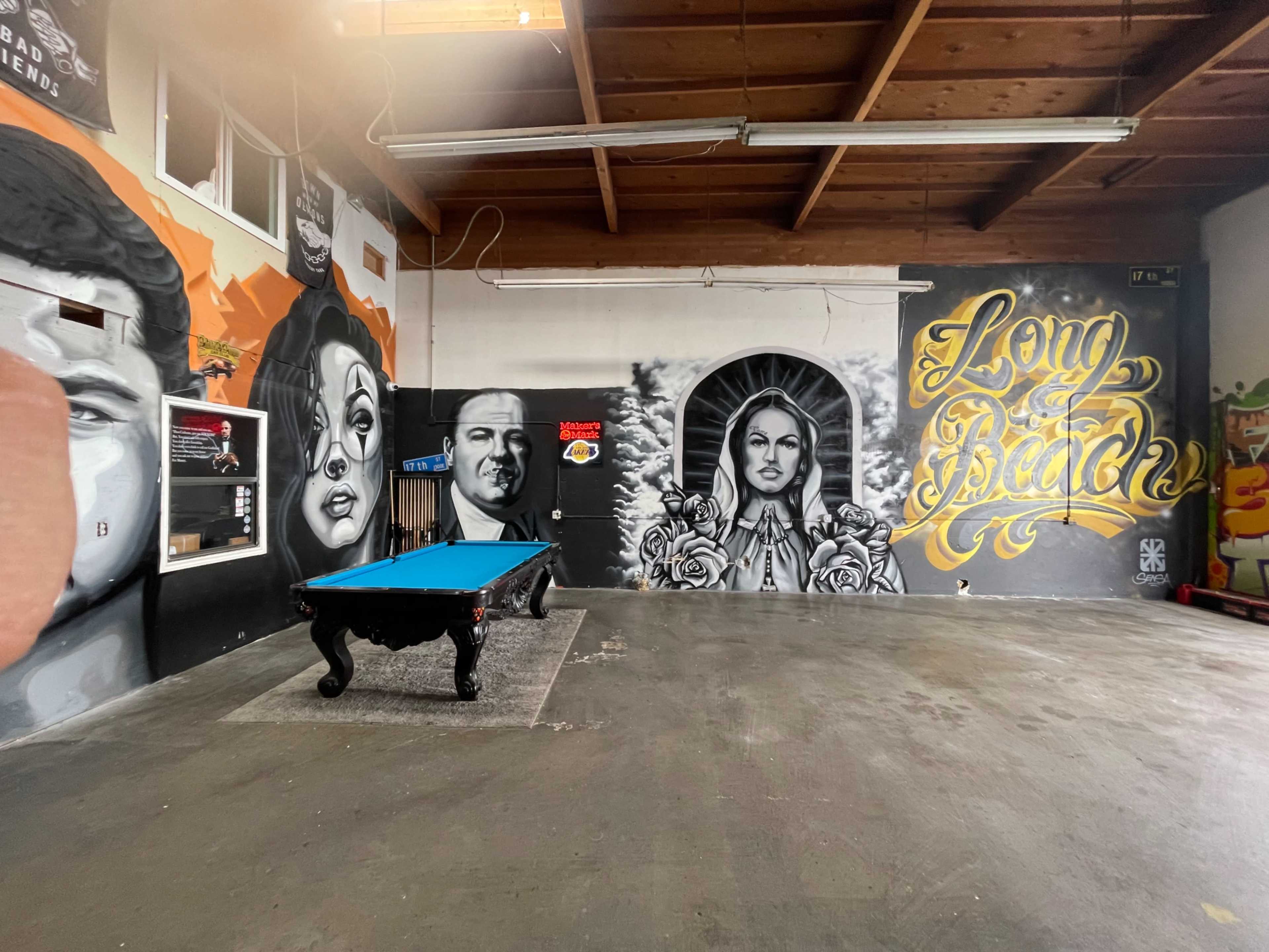 An indoor space featuring a billiard table and several large murals on the walls.