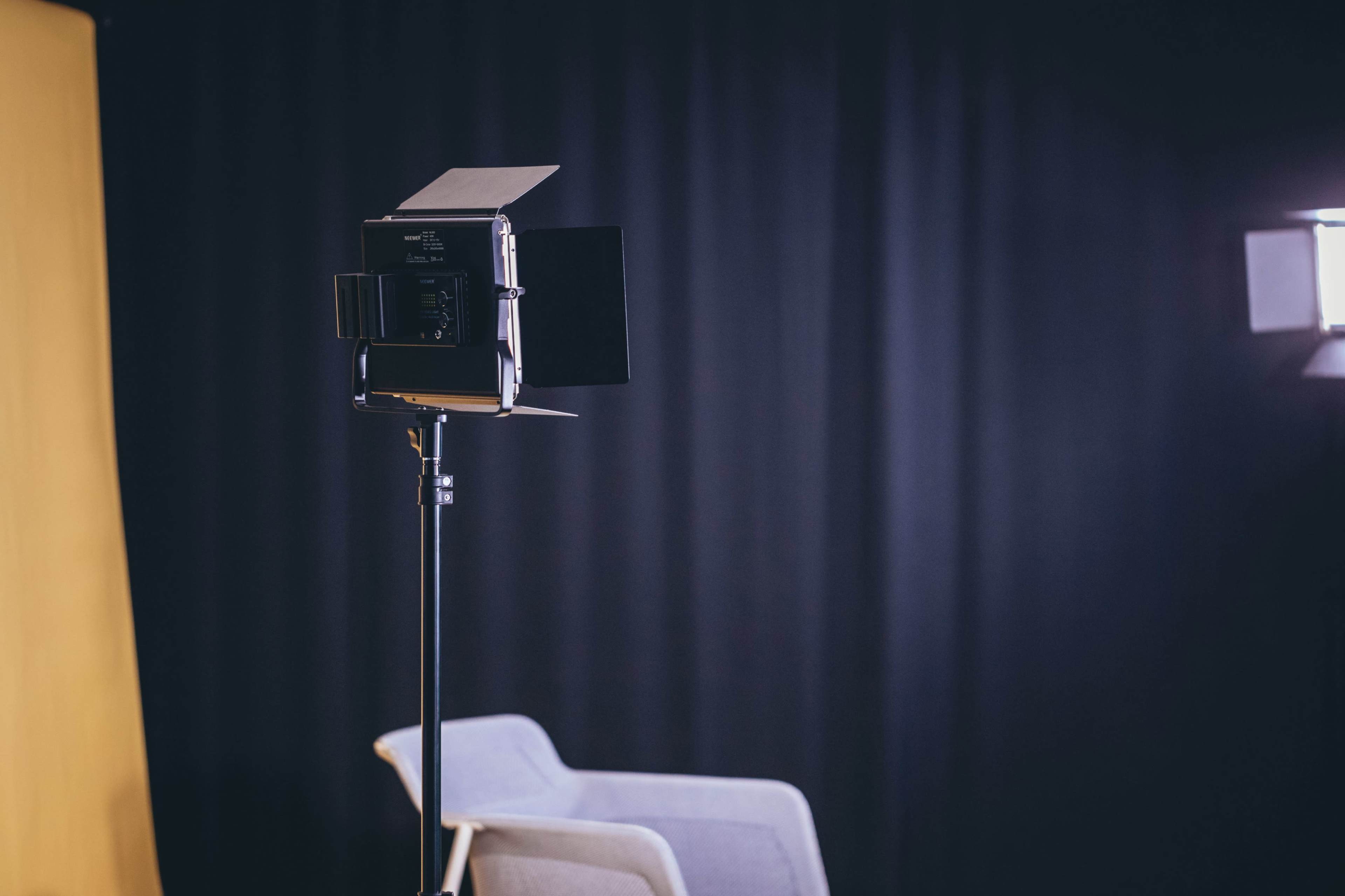 A lighting setup and a gray chair against a dark backdrop in an indoor setting.