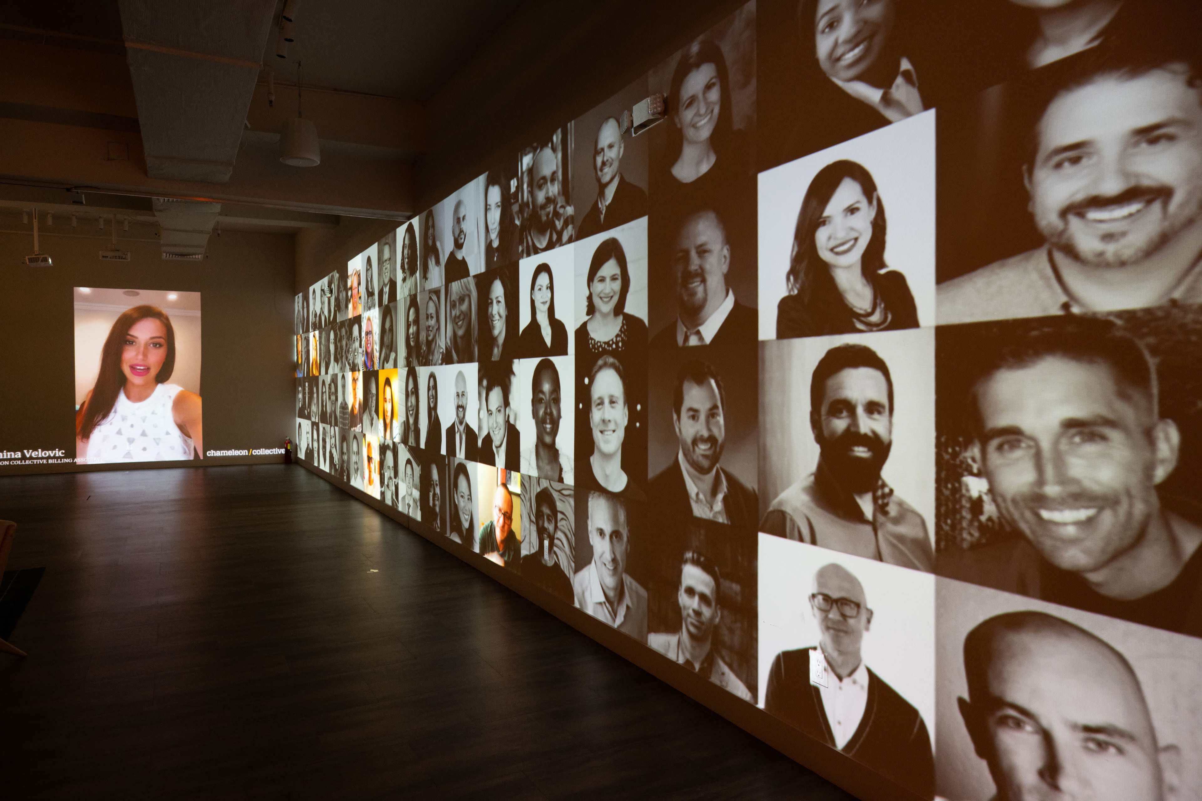 A wall of projected photographs displaying various faces, with a larger image of a woman on the left side.