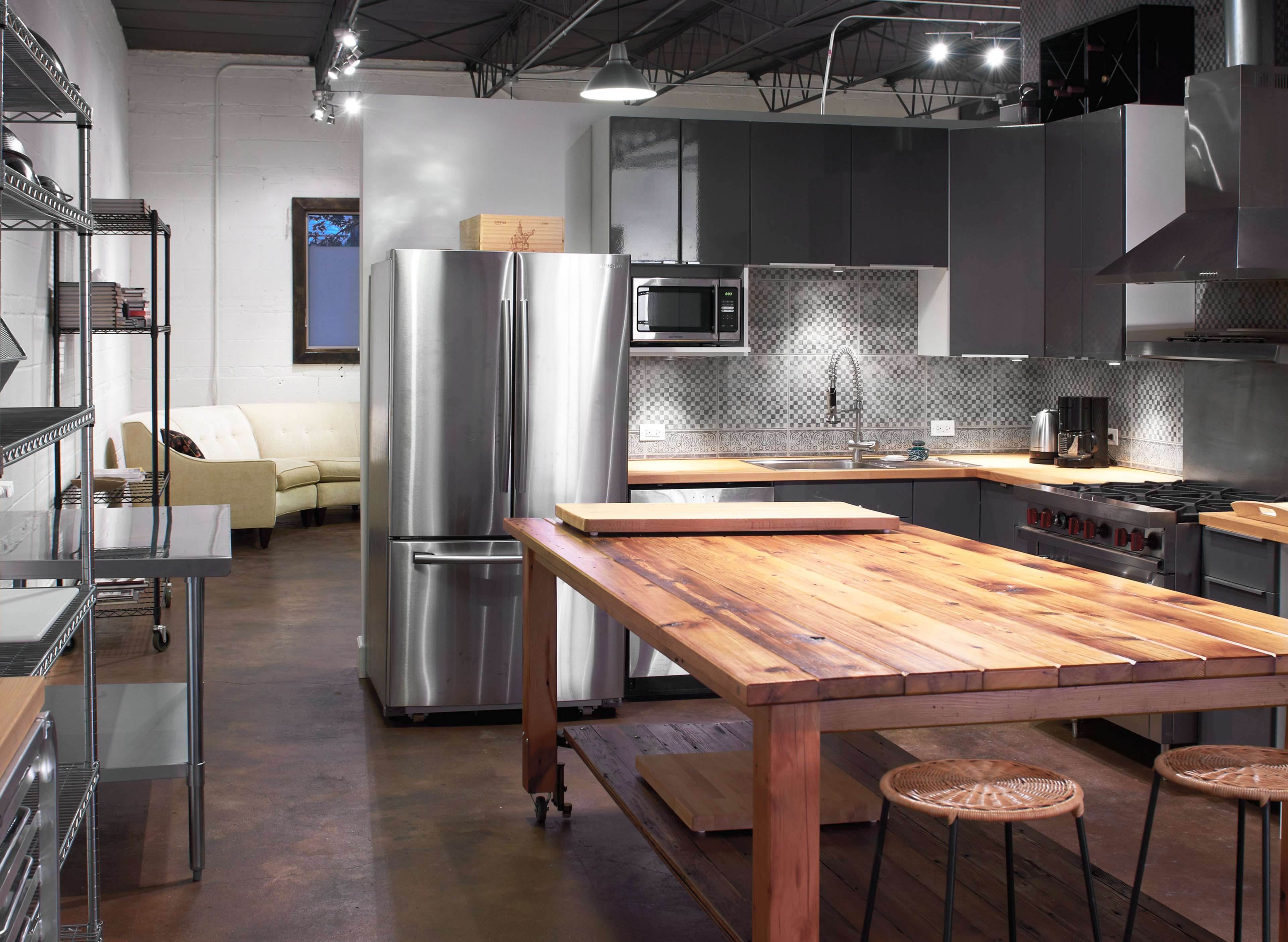 A modern kitchen with stainless steel appliances, a large wooden island, and a comfortable seating area in the background.