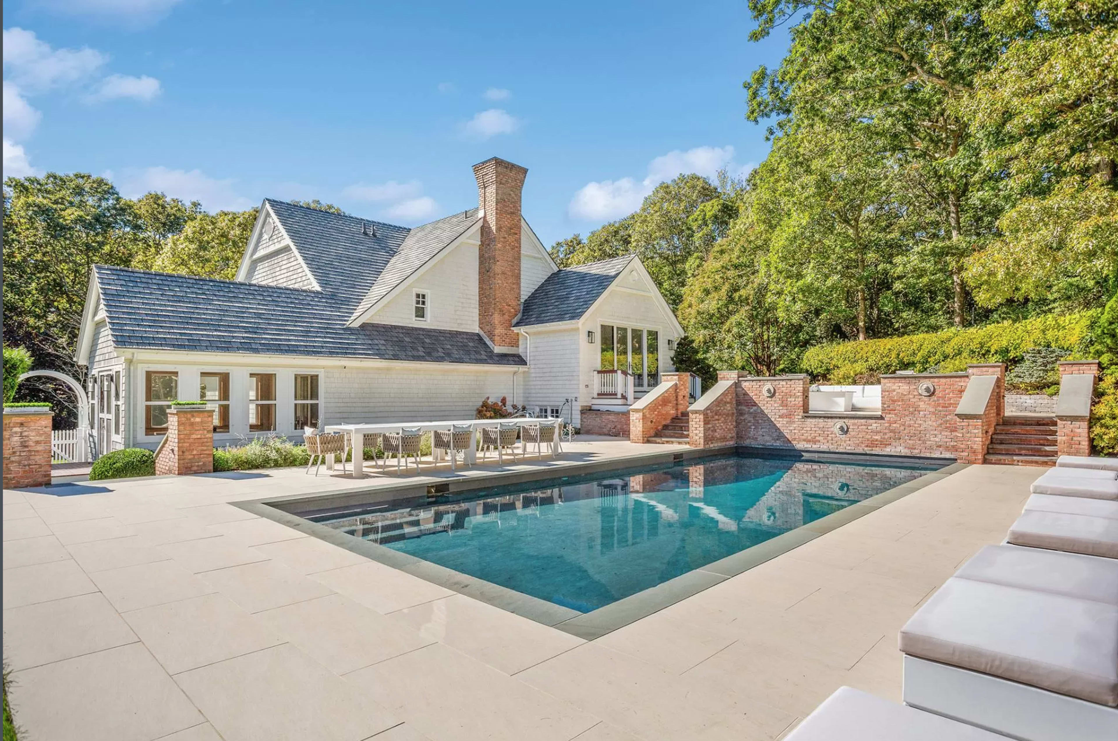 A modern home with a large swimming pool and a patio area surrounded by trees and landscaping.