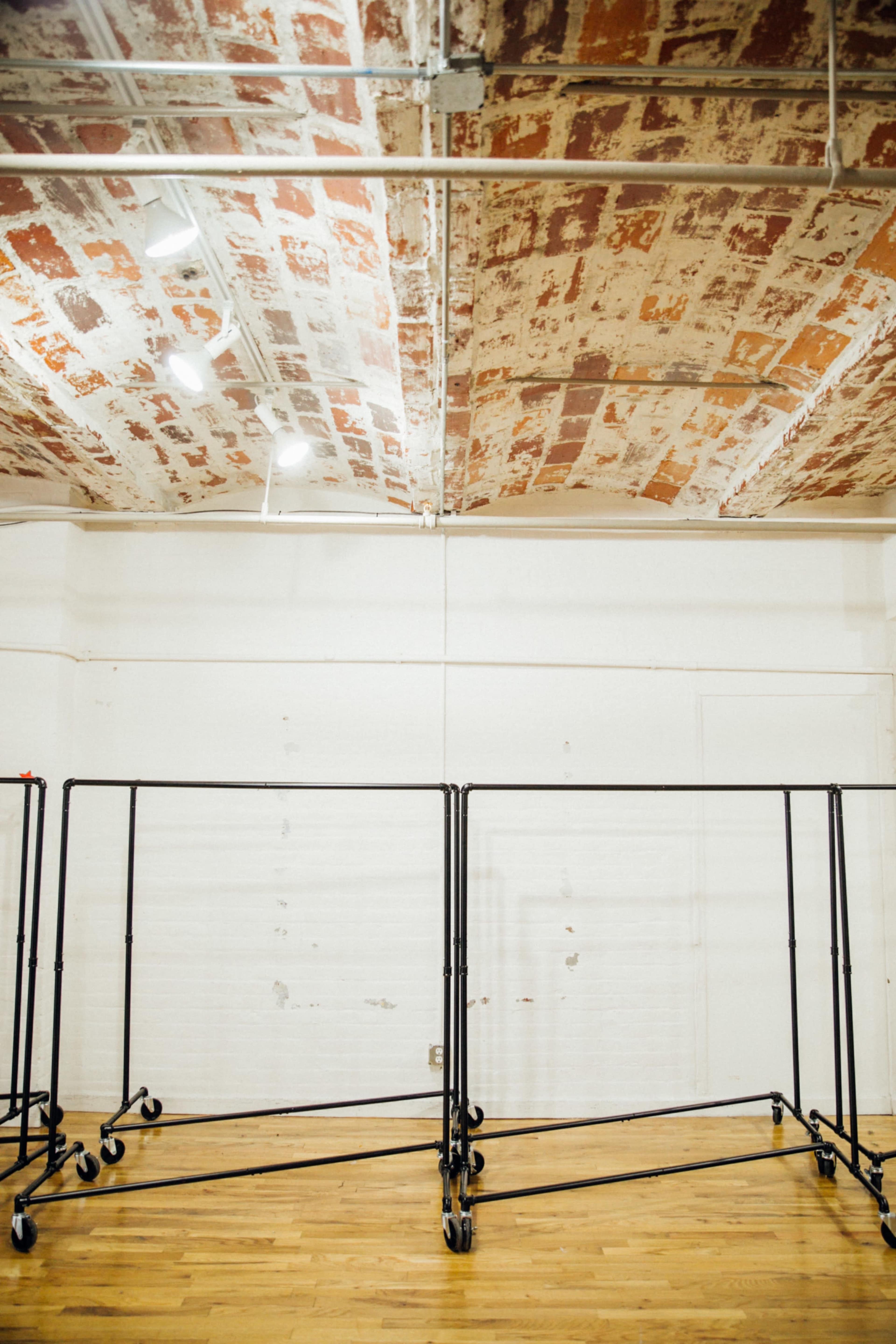 A minimalist room with a wooden floor and industrial-style clothing racks on wheels.