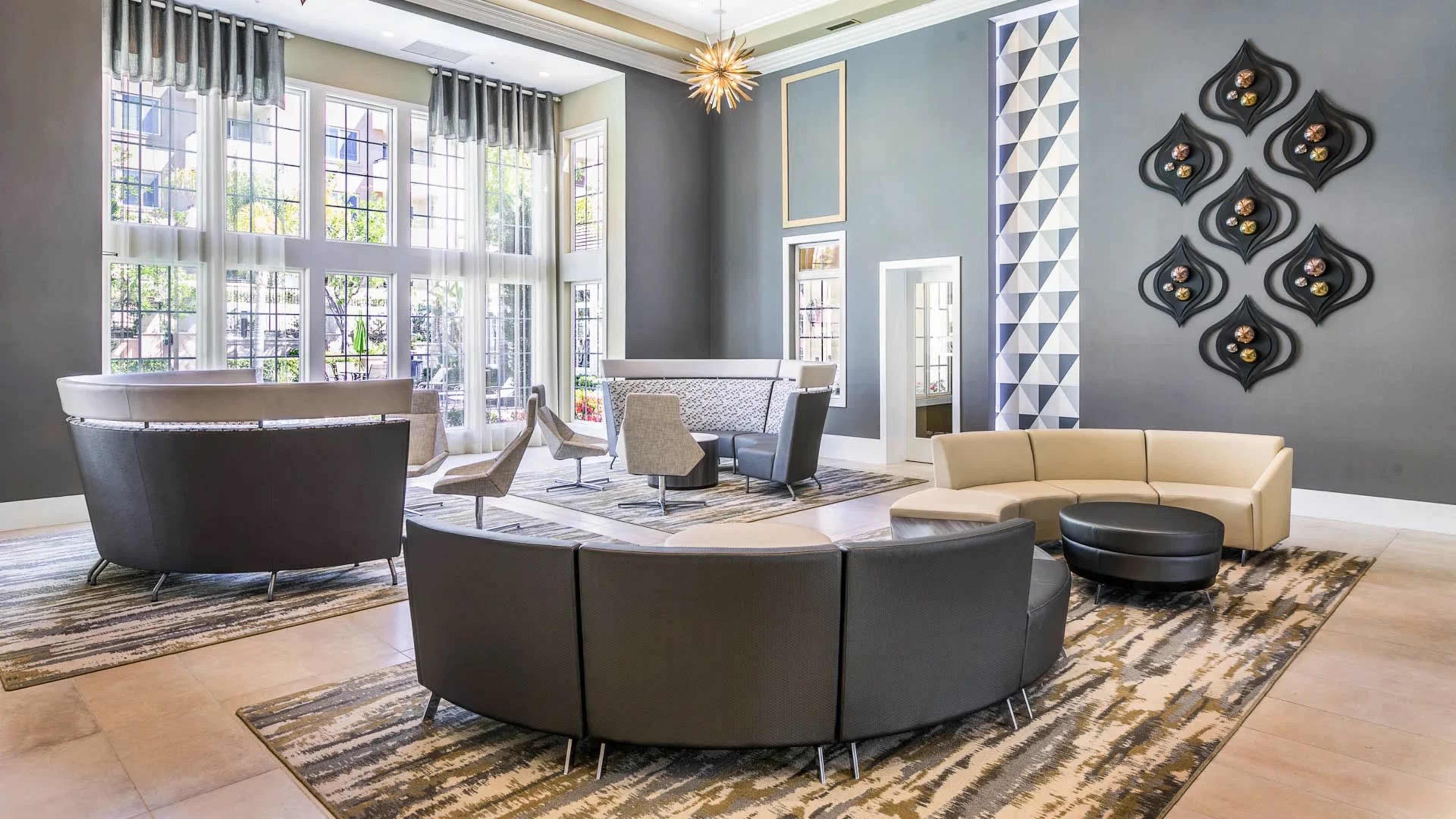 A modern lounge area with a circular seating arrangement, high windows, and decorative wall accents.