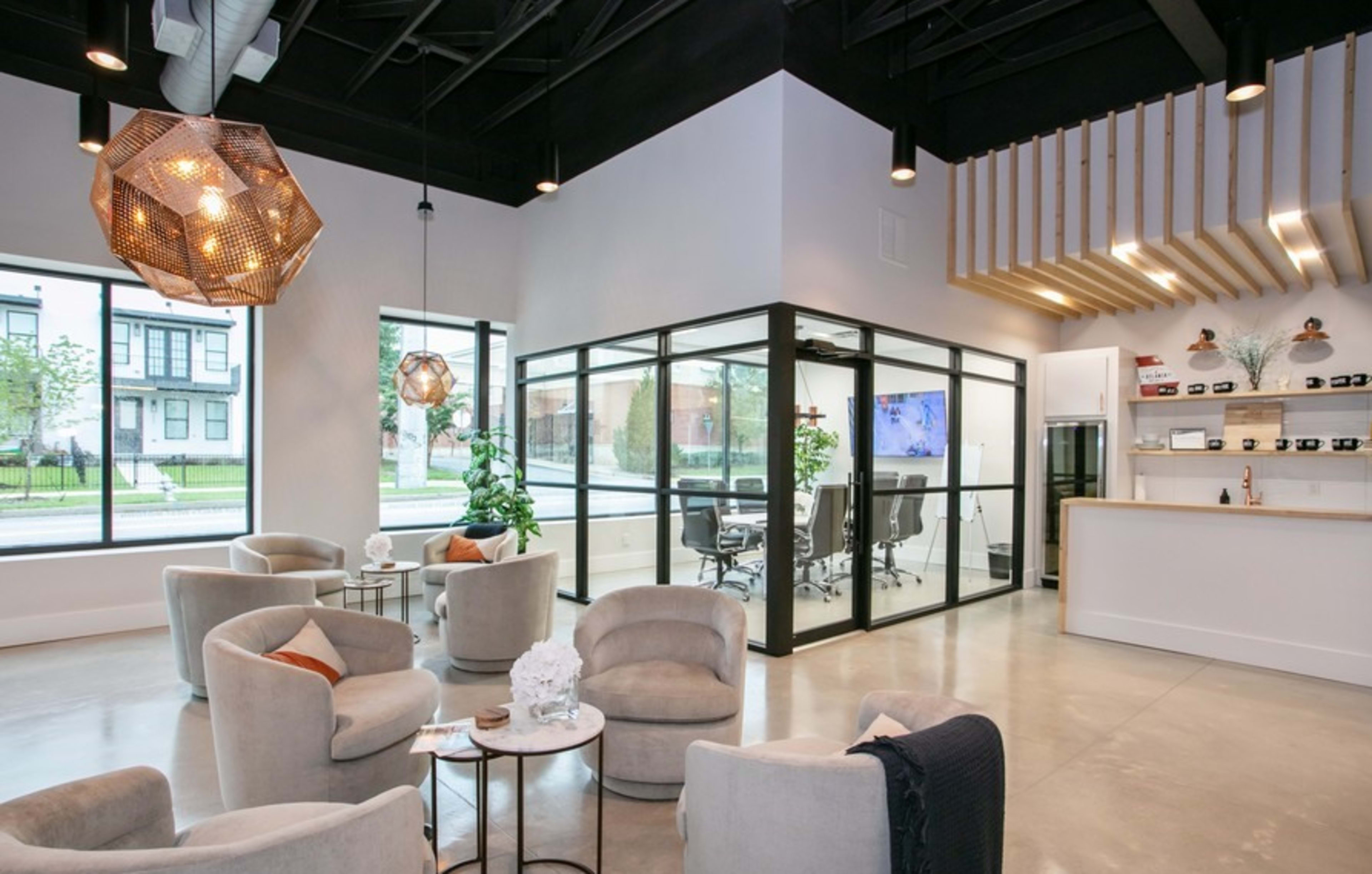 A modern office space with a glass-walled conference room, comfortable seating areas, and decorative plants.