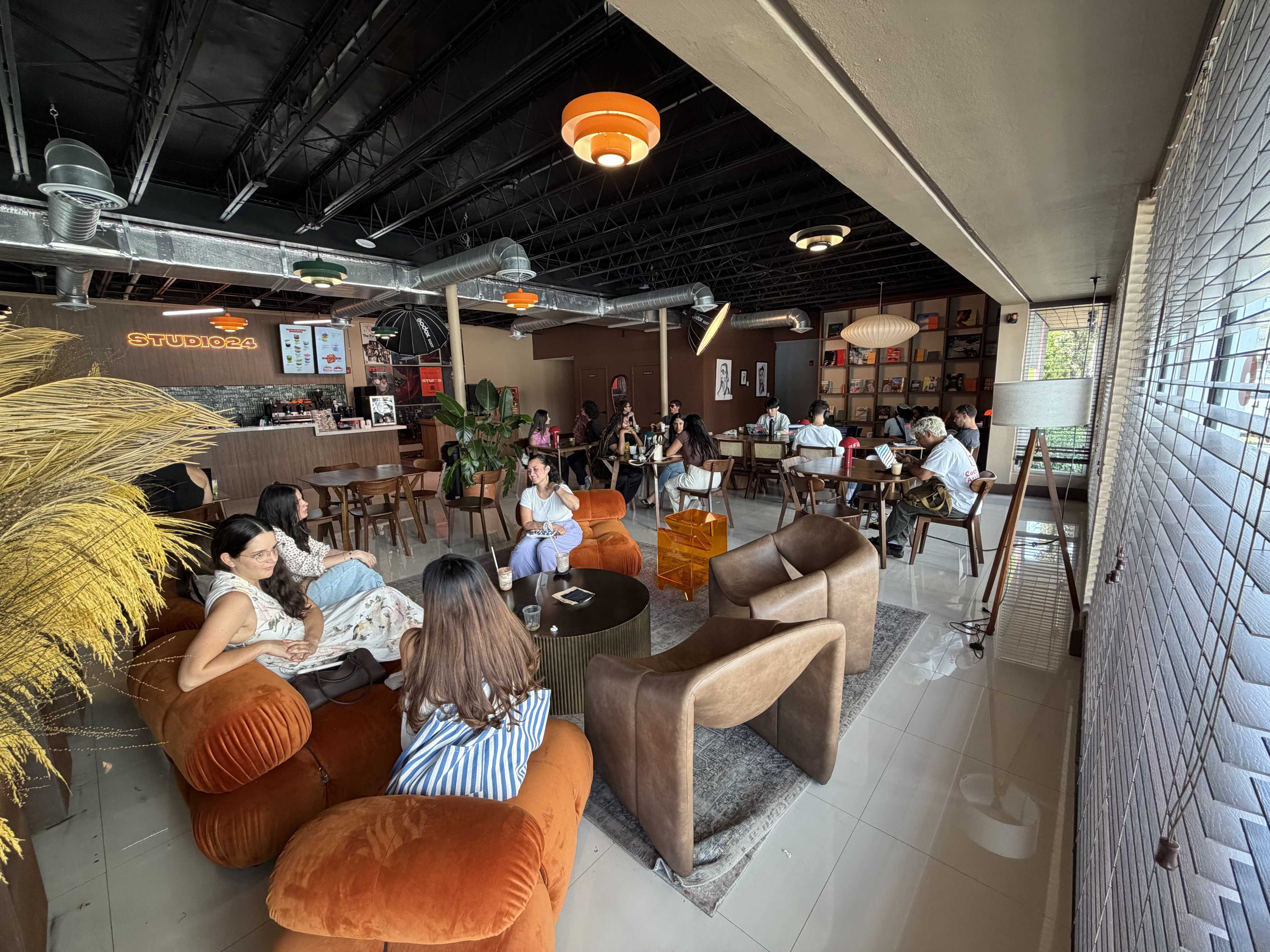 A modern café interior features various seating arrangements with patrons engaged in conversation and enjoying their time.