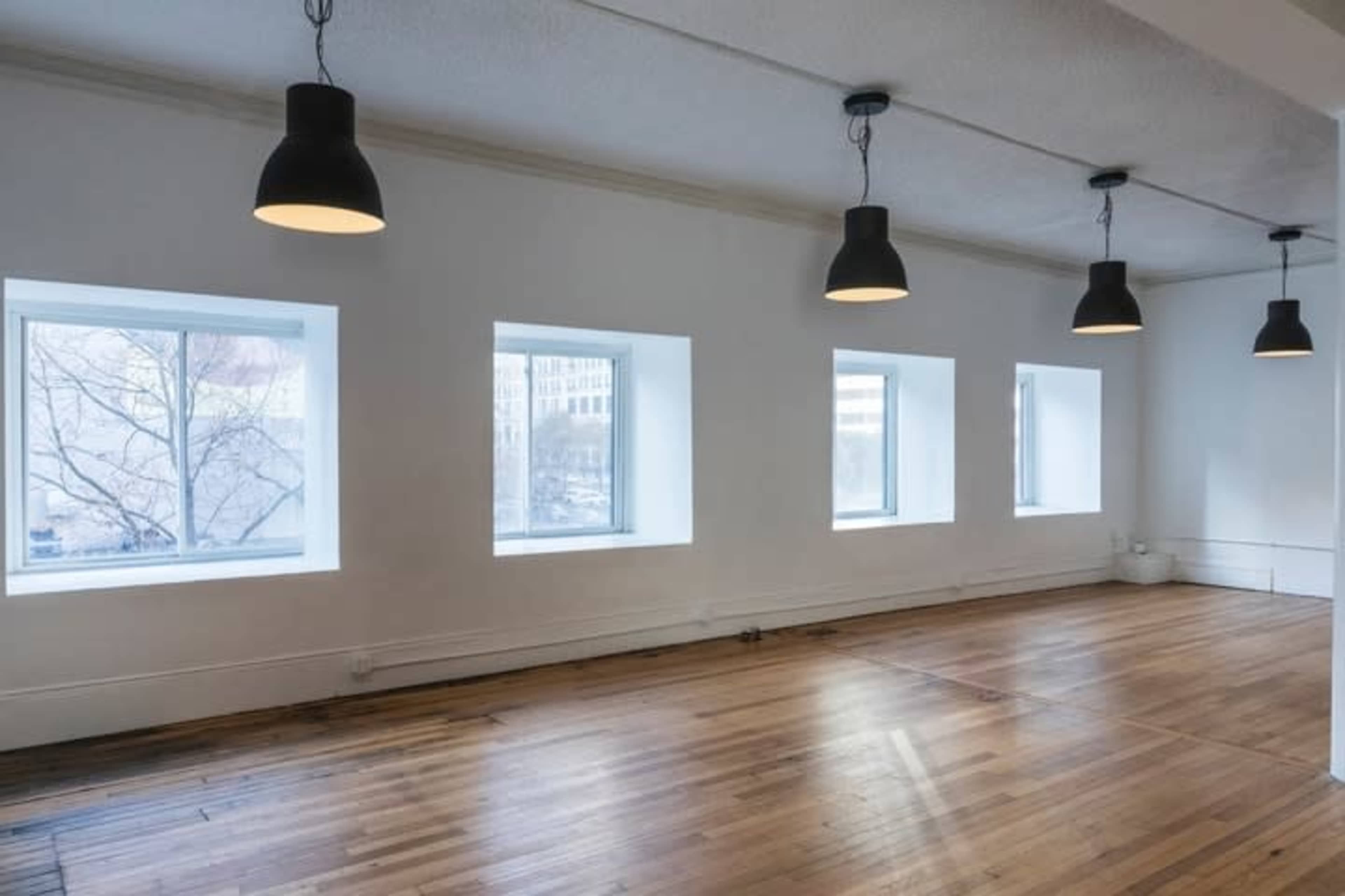 The image shows an empty room with four windows and pendant lights hanging from the ceiling.