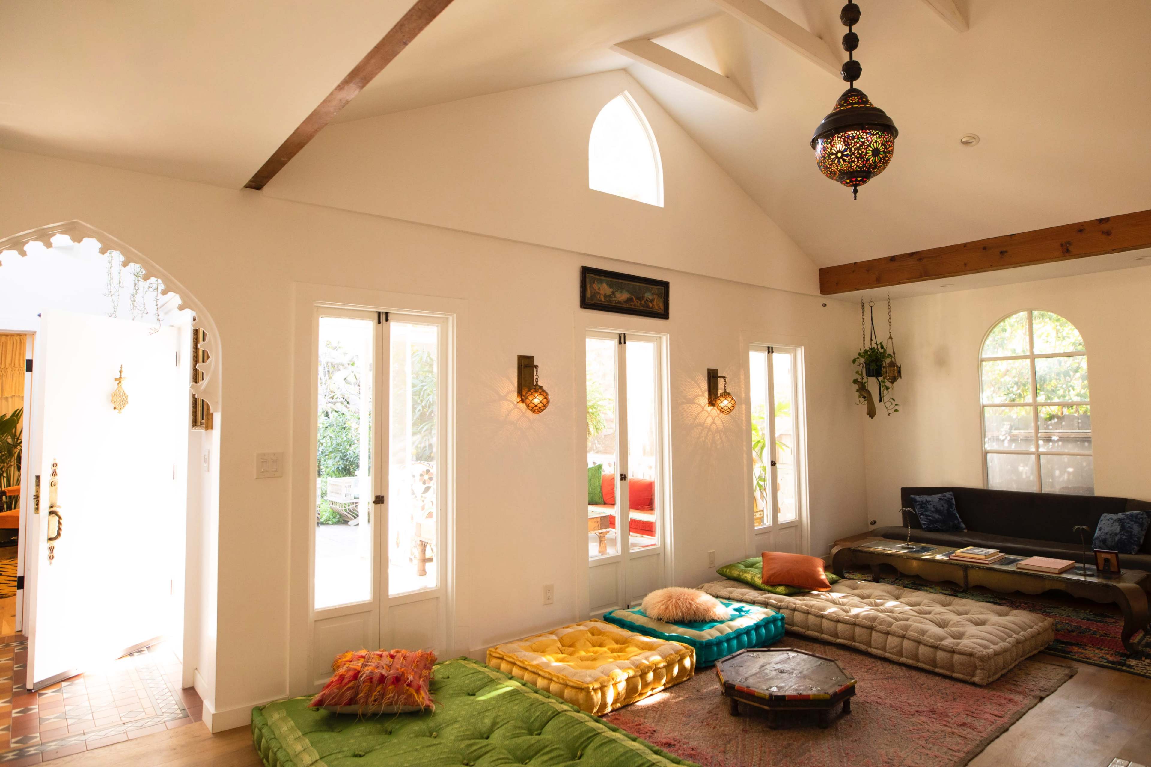 The room features a bright, open space with low seating and large windows, adorned with decorative light fixtures.