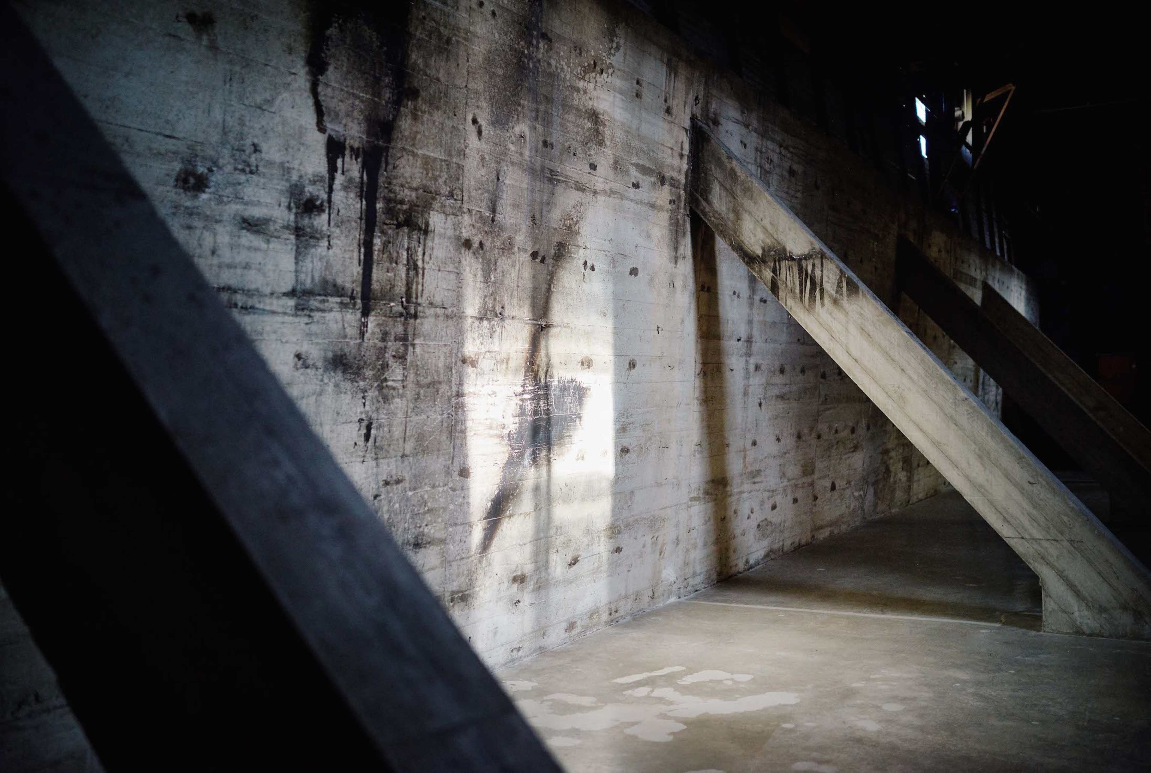 A concrete wall with diagonal wooden supports and a beam of light illuminating part of the surface.