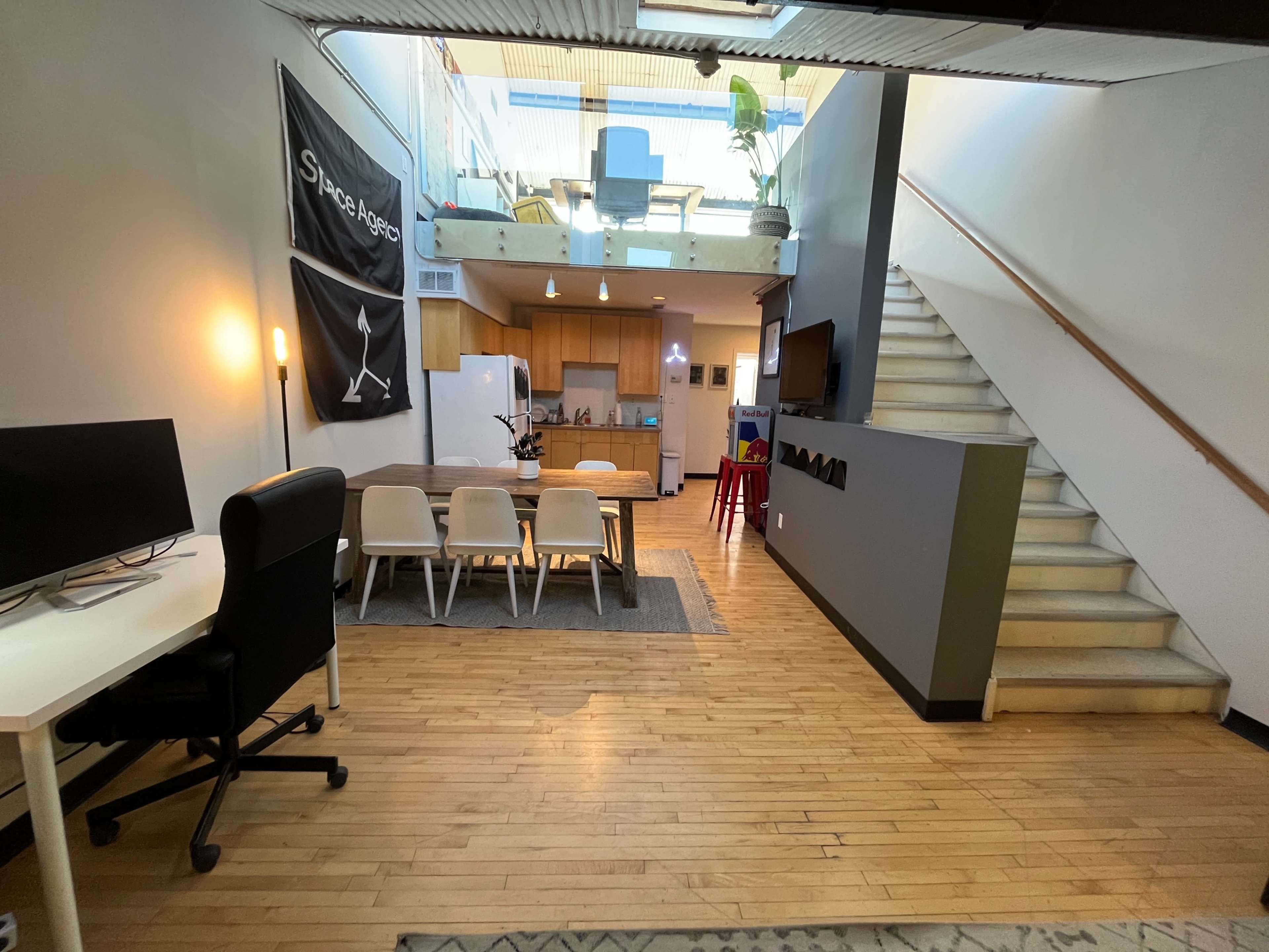 A spacious, modern living area with a dining table, kitchen, and a staircase leading to an upper level.