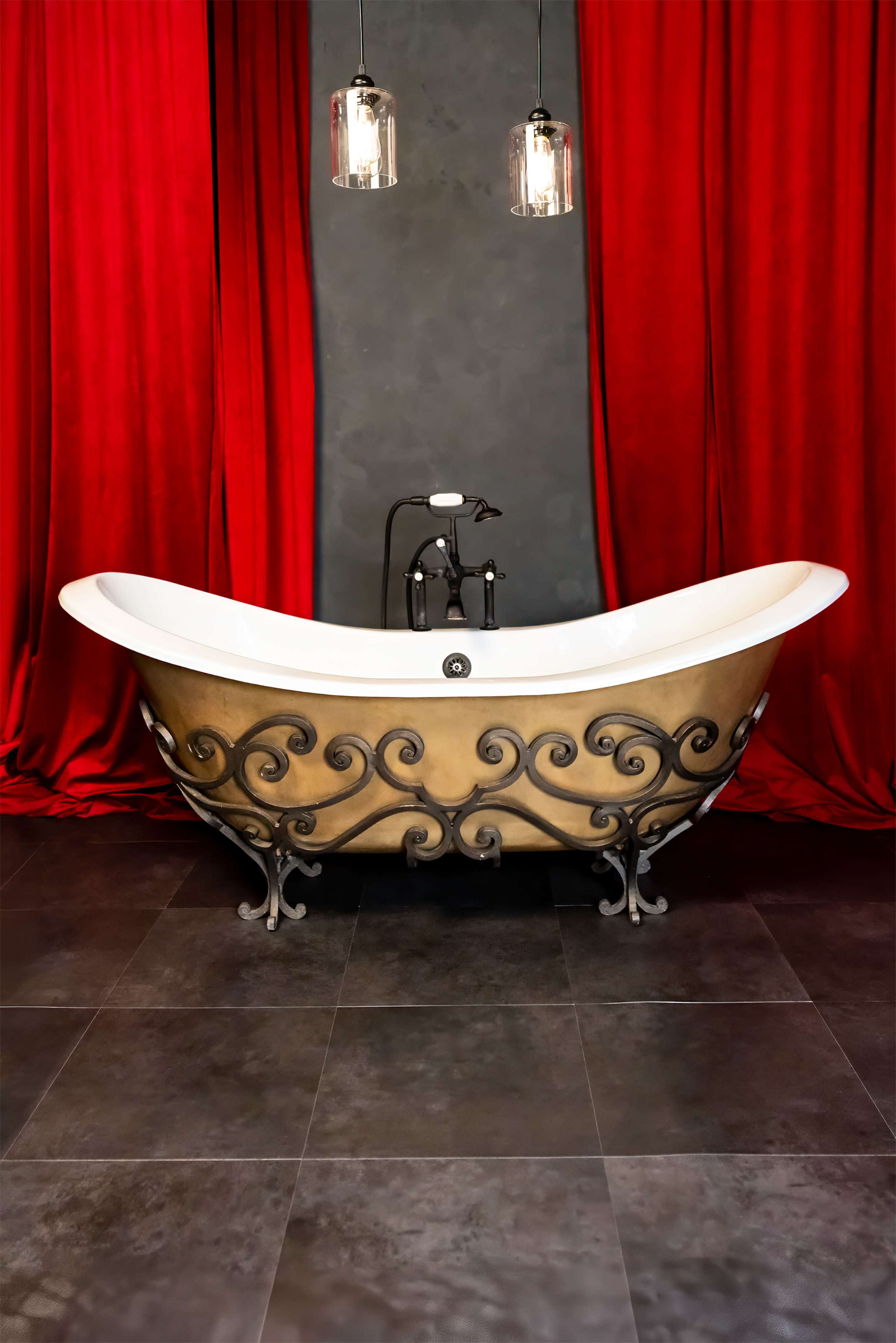 A vintage-style freestanding bathtub with ornate metal detailing is placed against a backdrop of red curtains and dark walls.