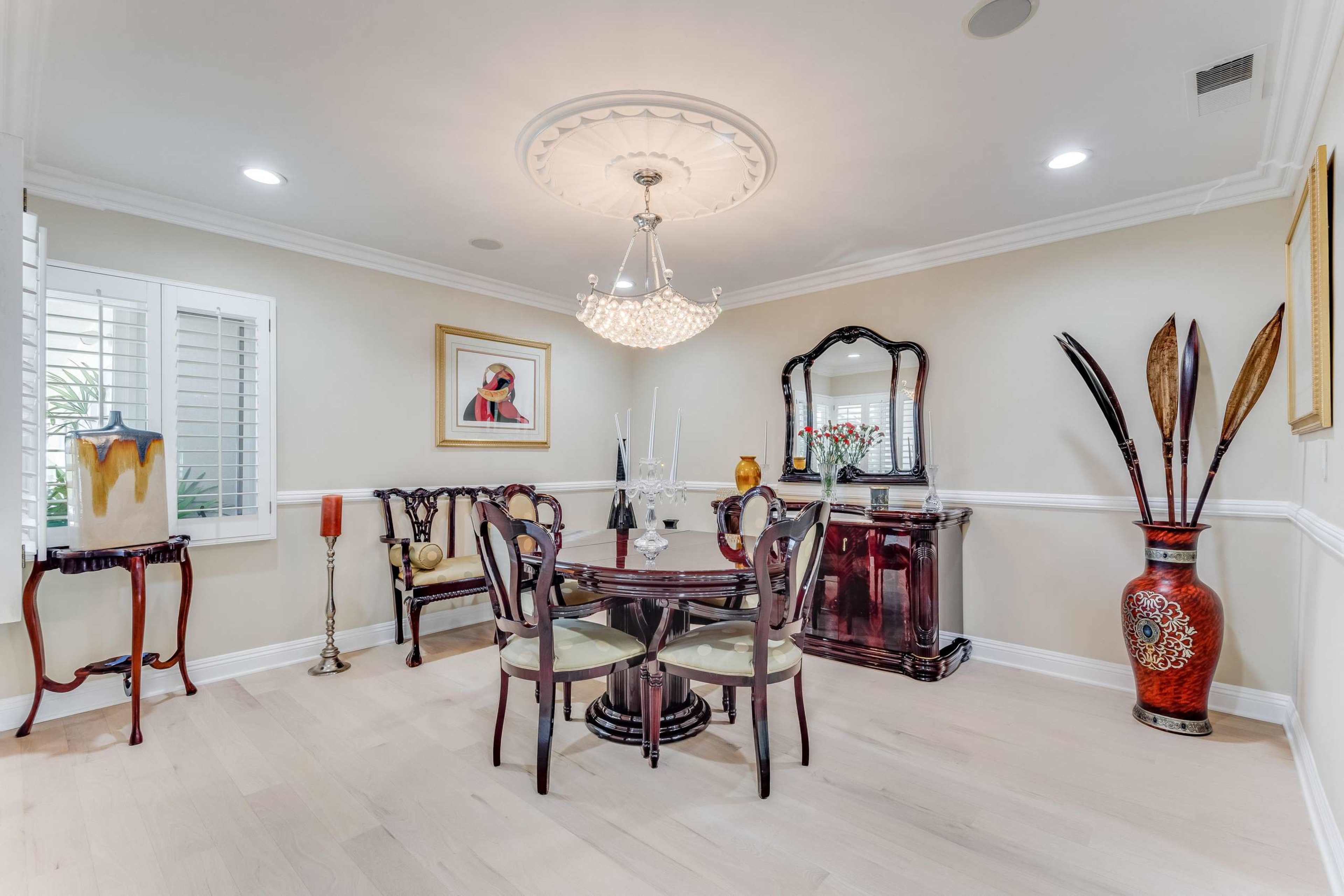 A stylish dining area featuring a round table surrounded by chairs, a decorative chandelier, and various pieces of artwork and decor.