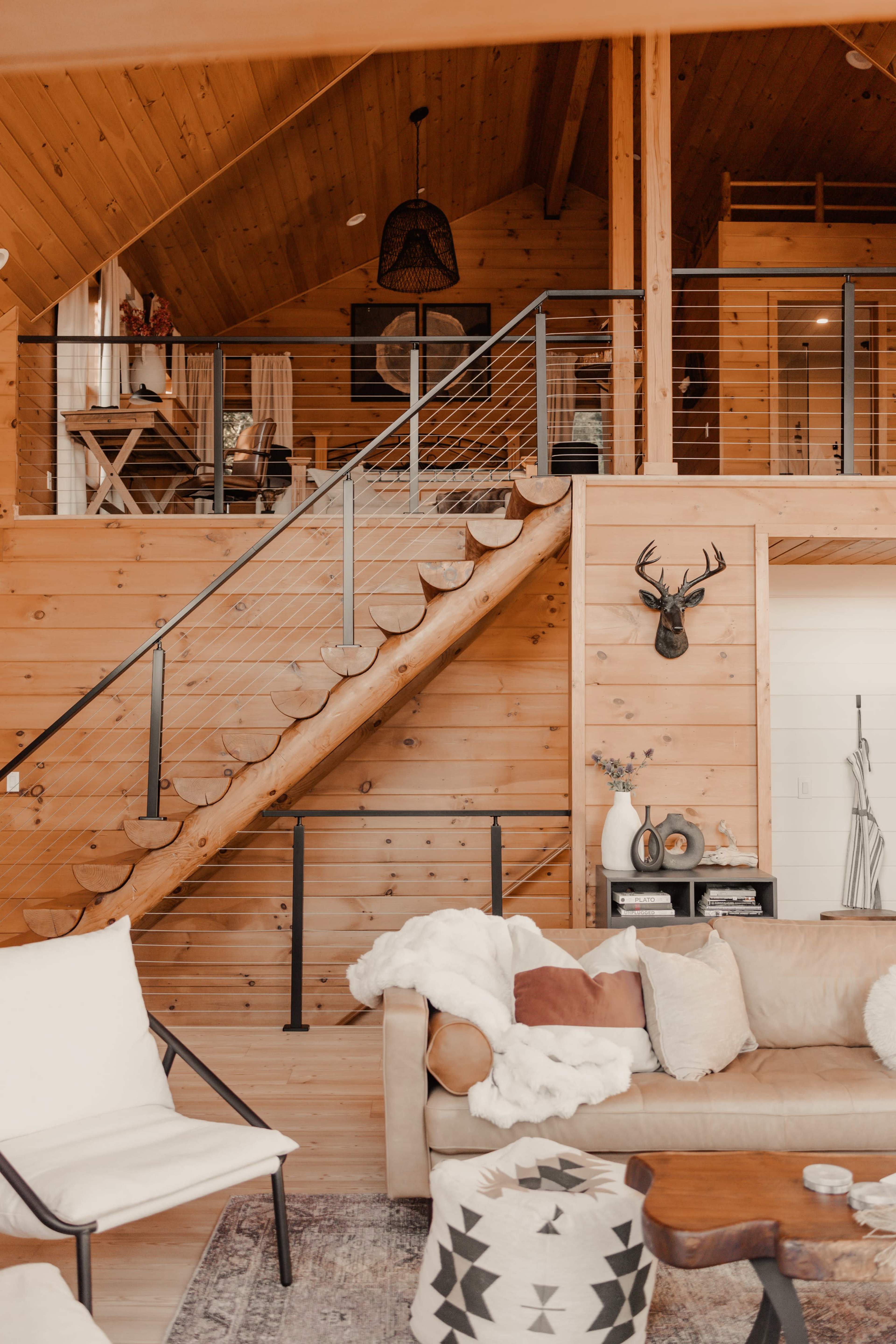 A wooden interior of a home featuring a staircase with a railing, a cozy seating area, and various decorative elements on the walls and furniture.
