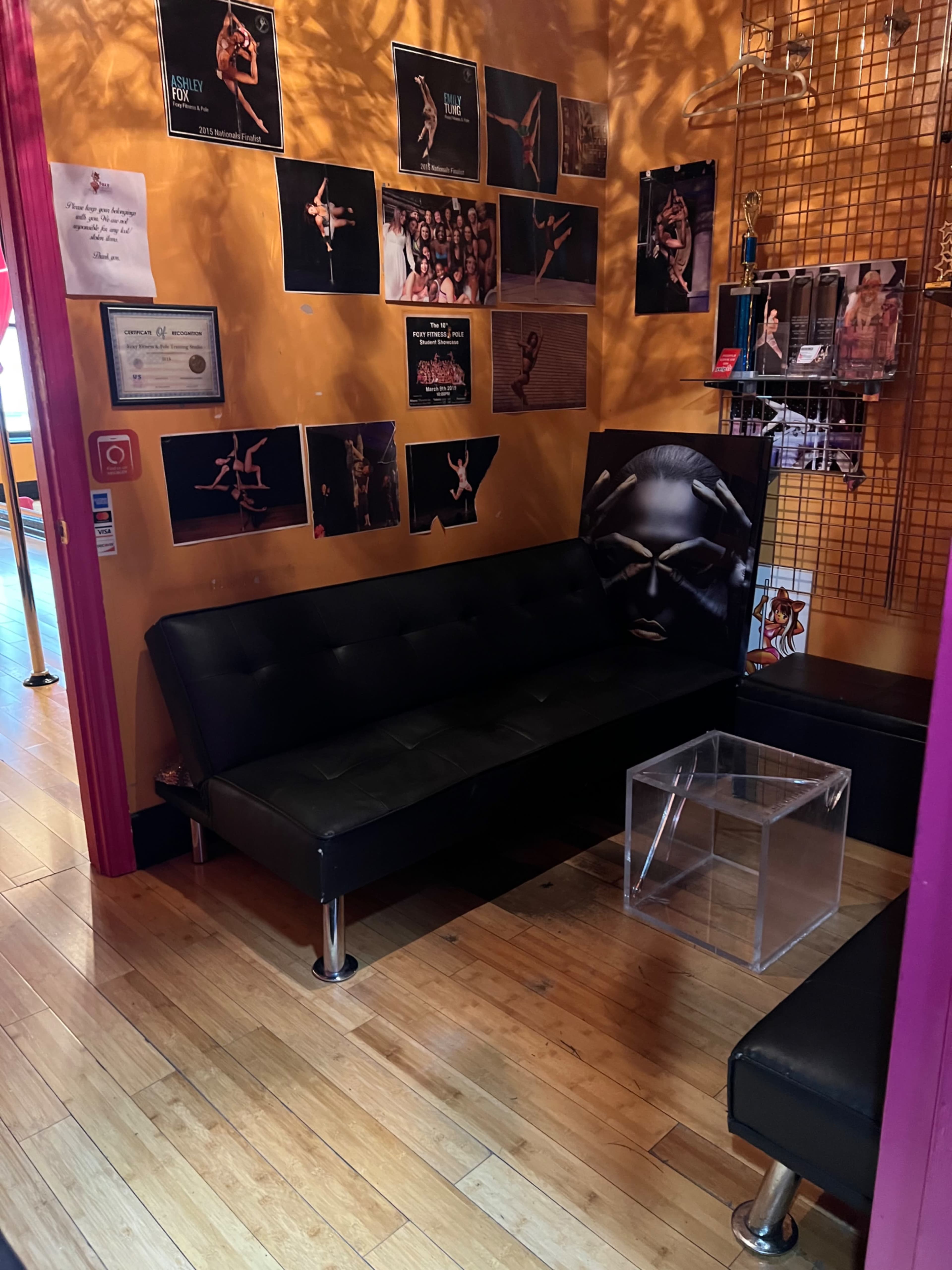 A vividly decorated waiting area featuring black sofas, framed photographs on the walls, and a clear acrylic table.