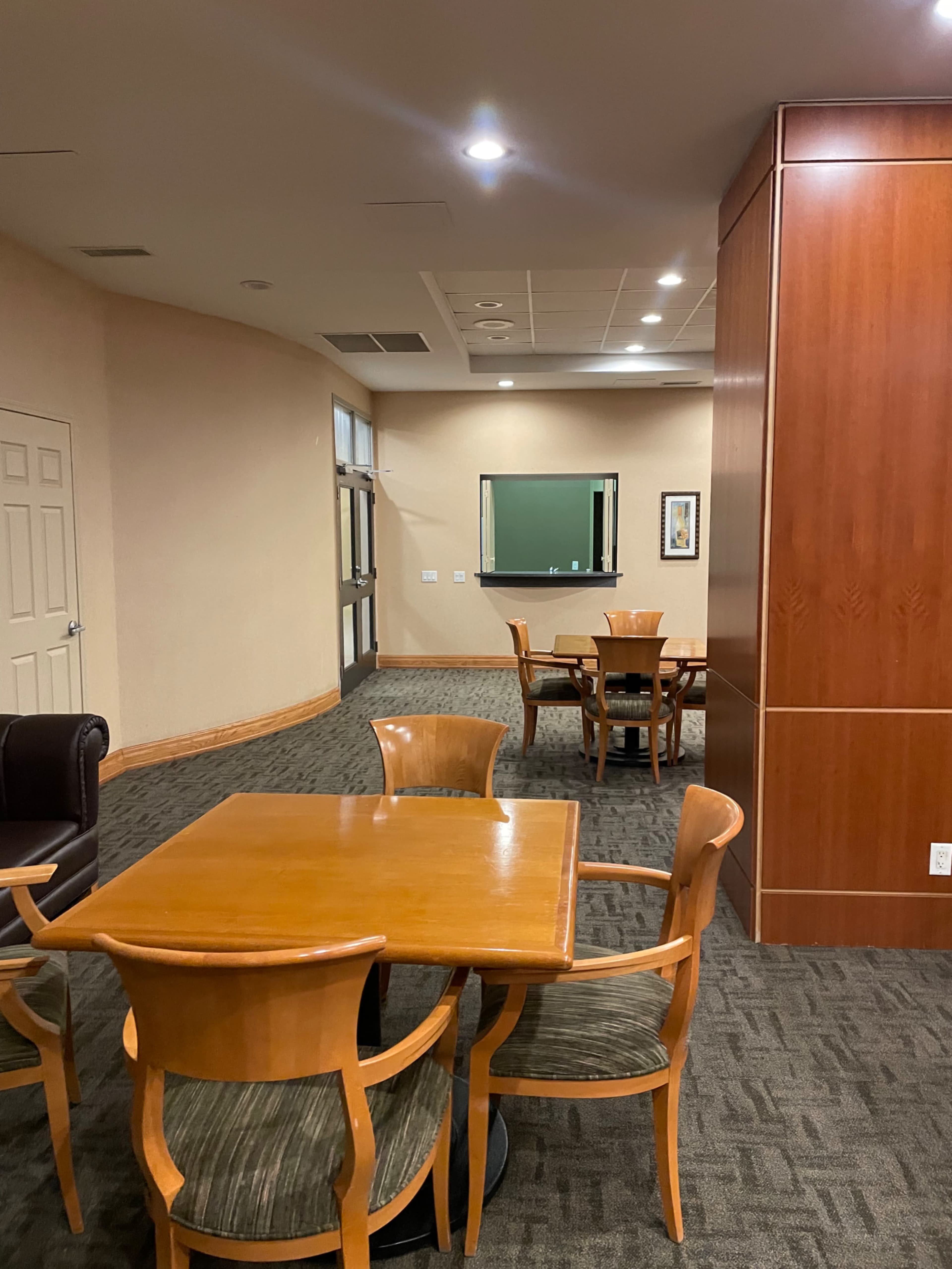 A spacious room with wooden furniture, including a table and chairs, and a large mirror on the wall.