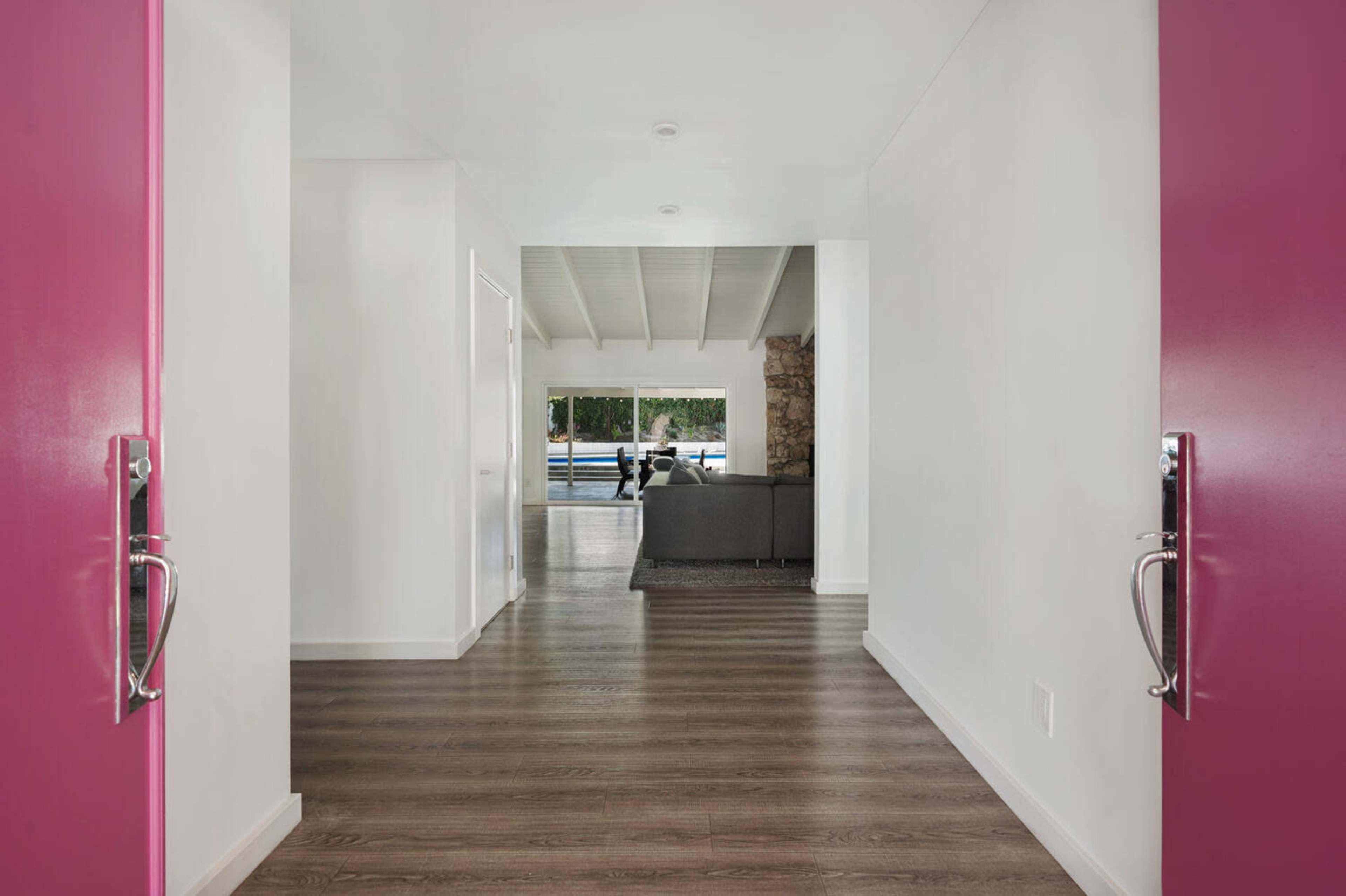 A view from a brightly colored entryway reveals a modern living space with a stone feature wall and large windows.