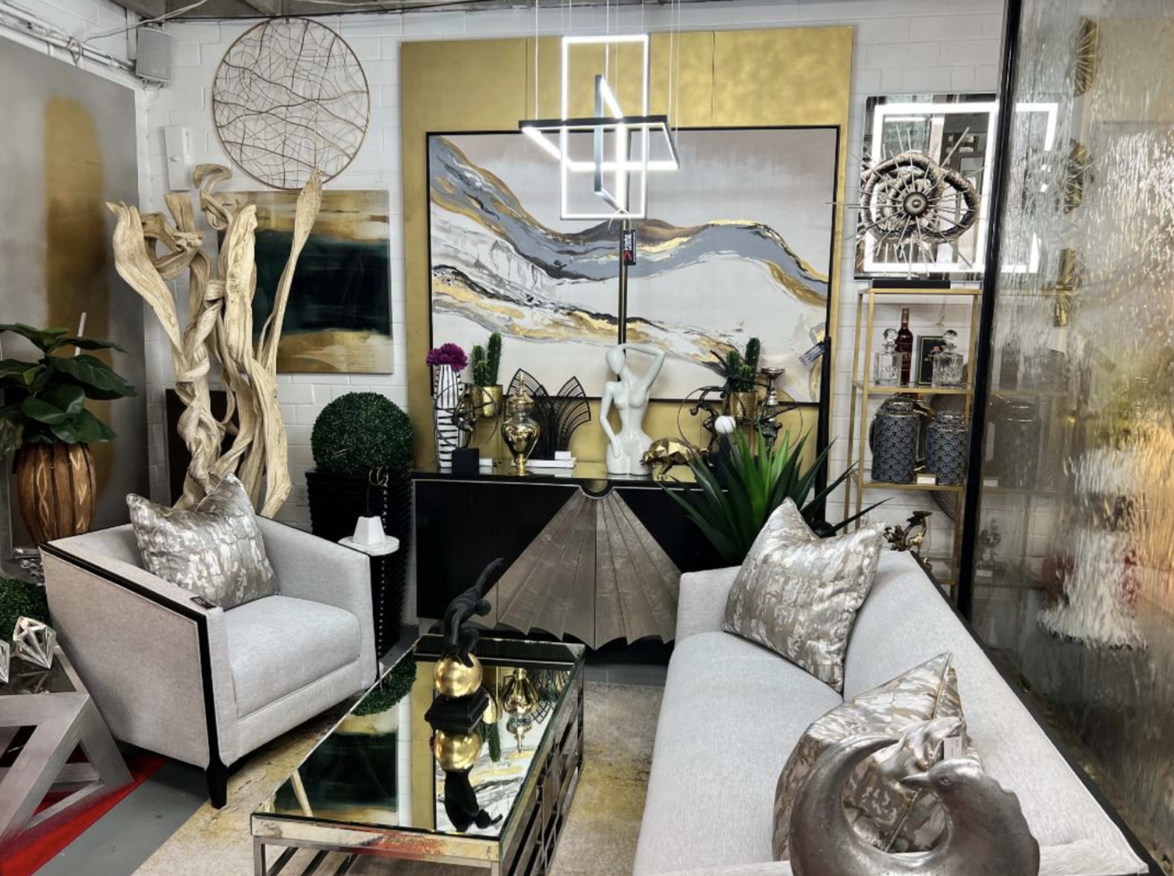 A modern living space with two gray armchairs, a reflective coffee table, and decorative artwork on the walls, surrounded by various plants and decorative objects.