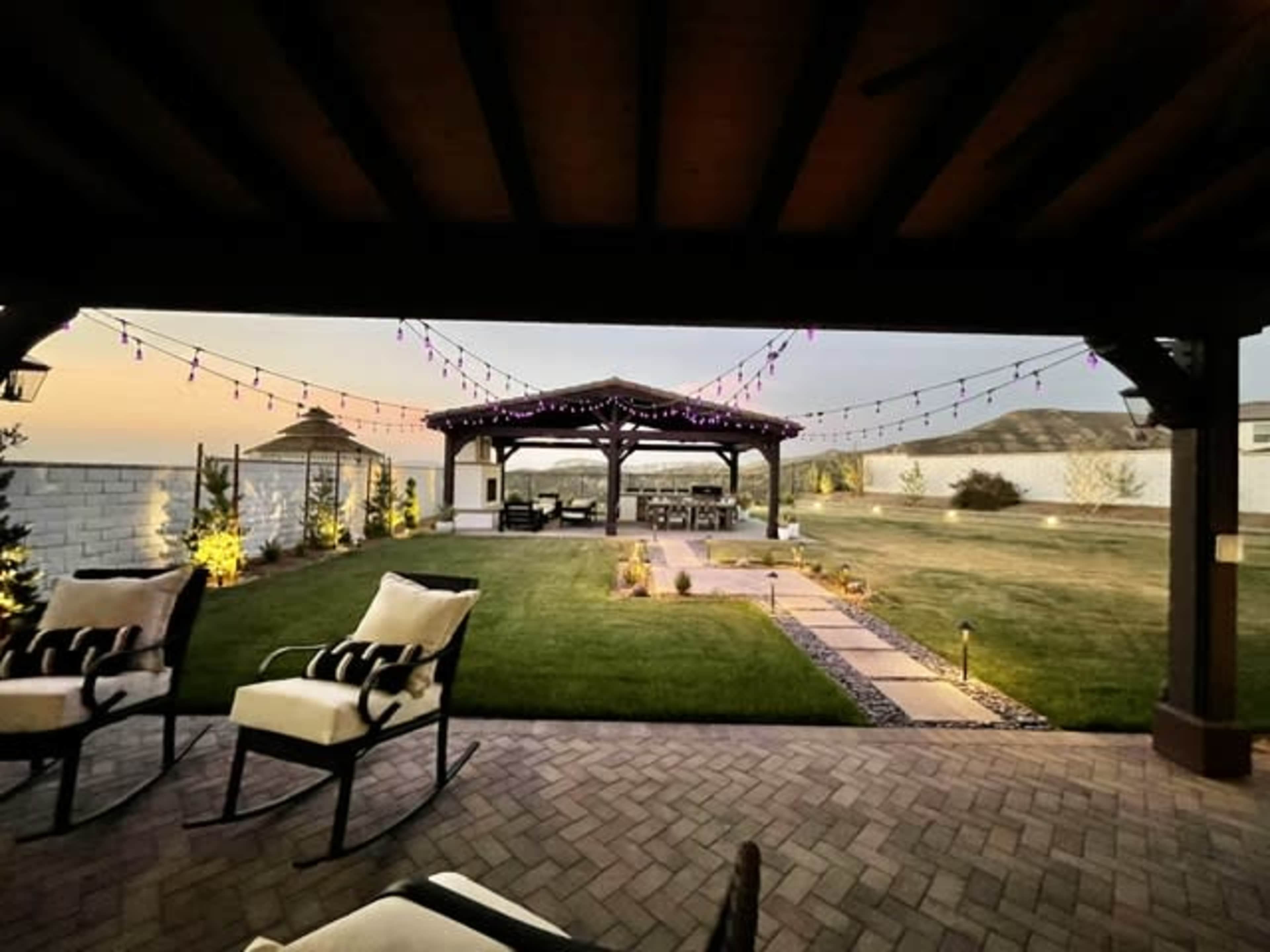The image shows a patio with a view of a gazebo surrounded by decorative string lights and landscaped grass in the background.