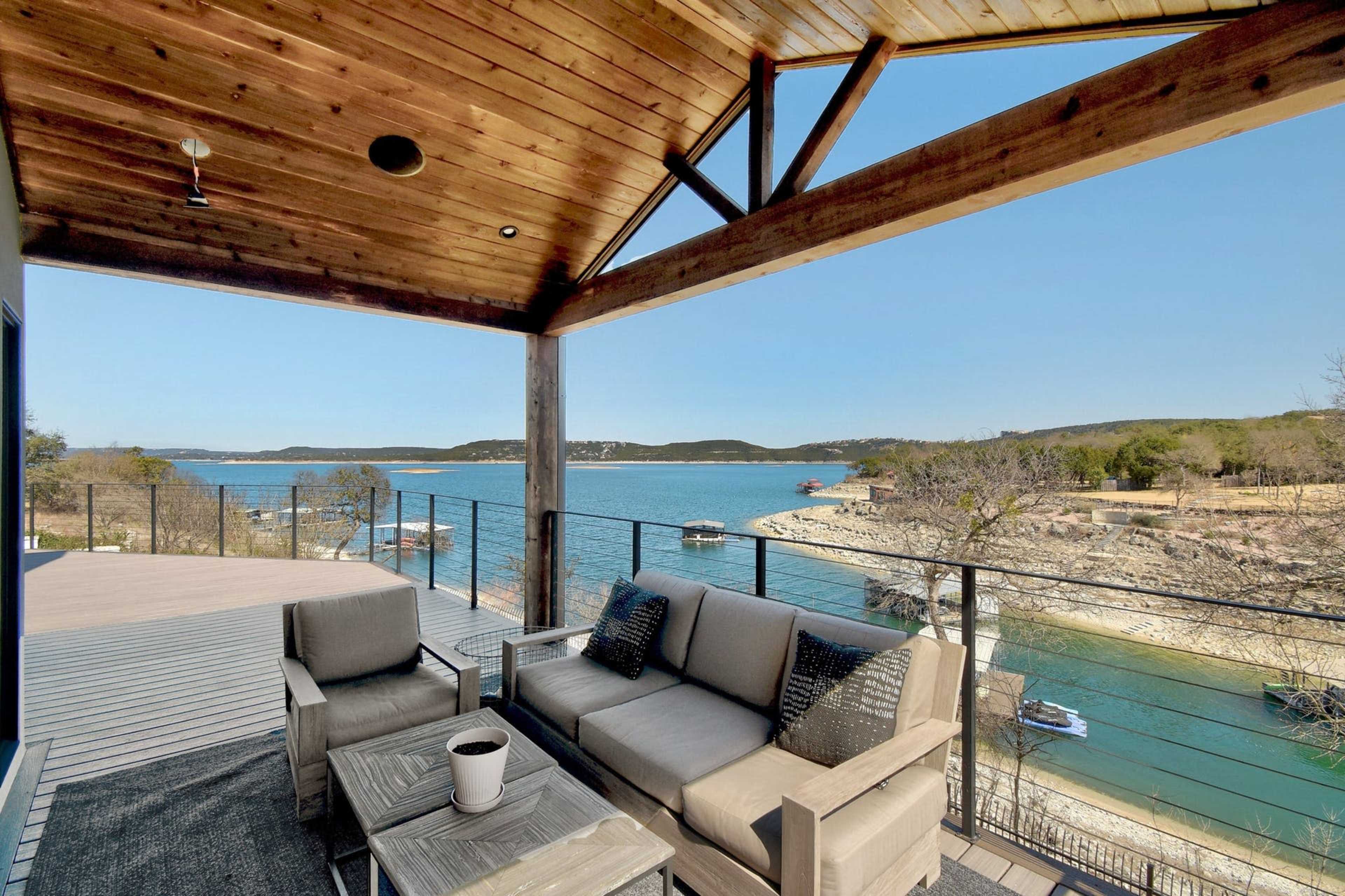 A covered outdoor seating area overlooks a lake surrounded by hills and boats.