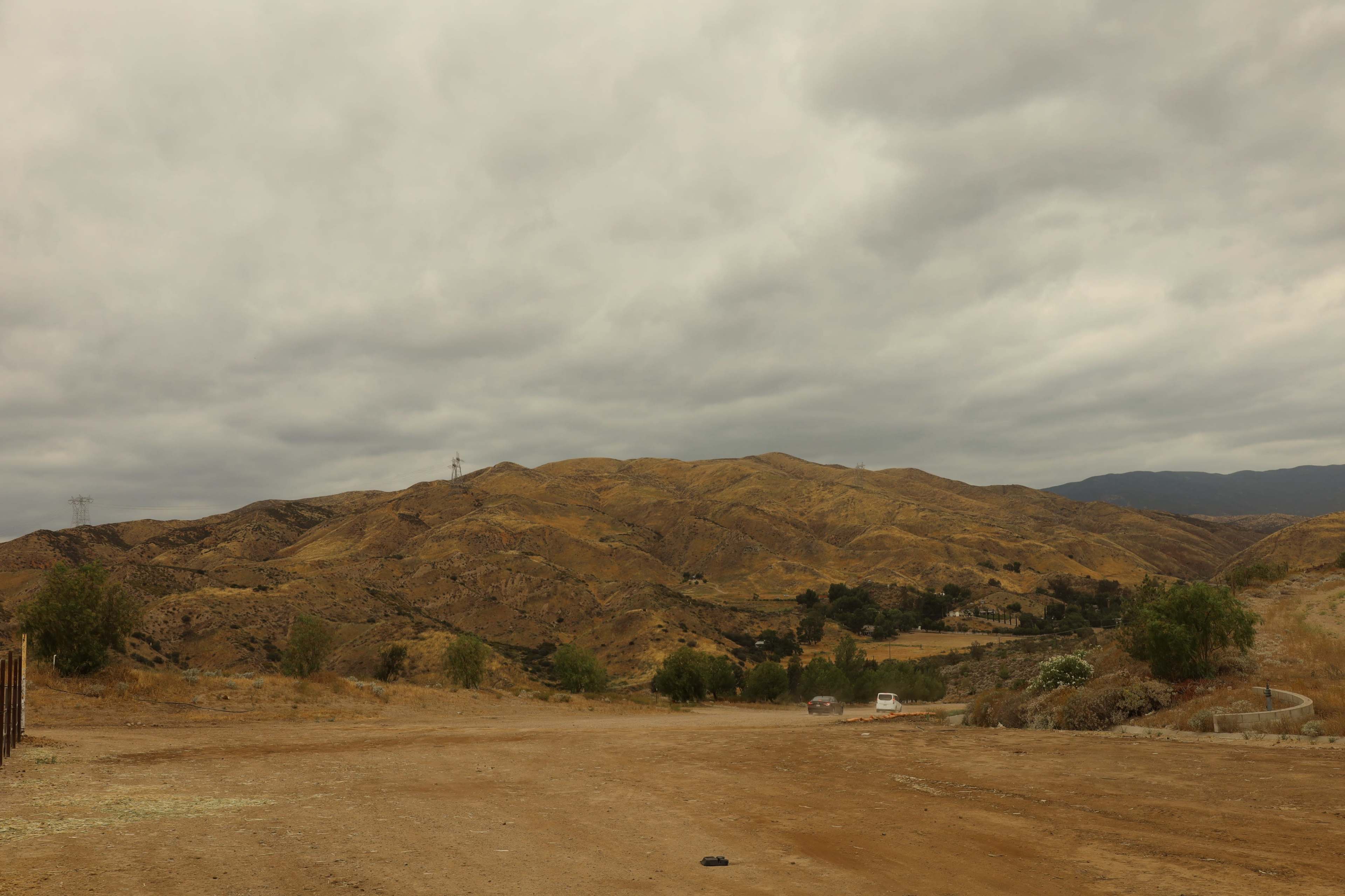 A barren landscape of rolling, dry hills and overcast skies stretches across the scene.